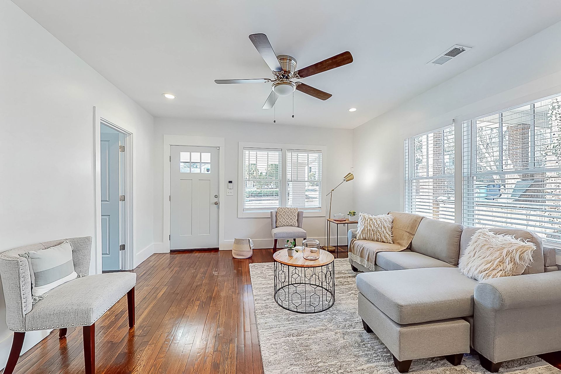 Living room with gray sectional sofa, hardwood floors, and large windows.