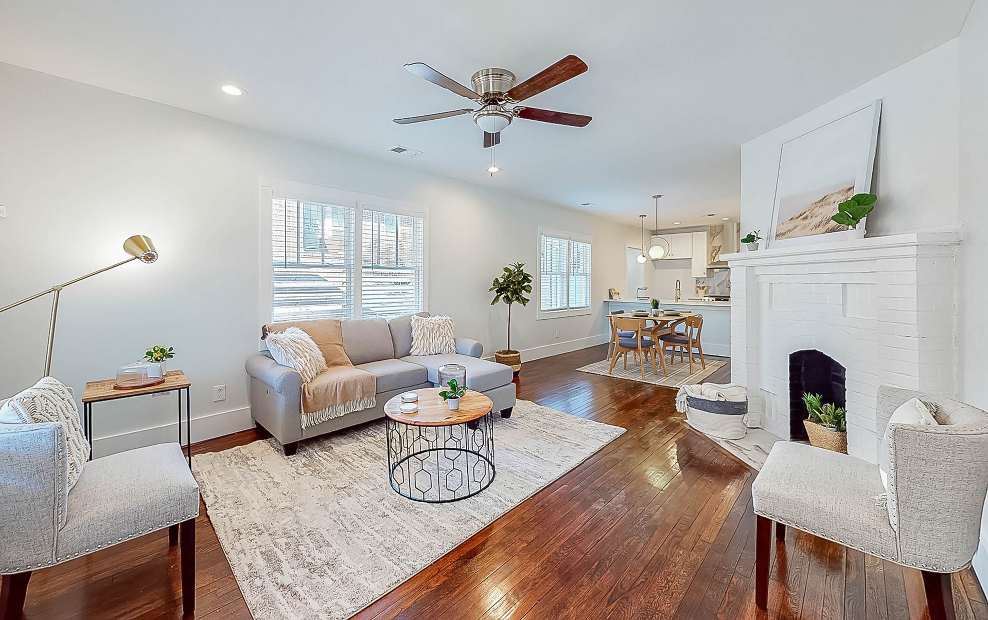 Living room with gray sofa, fireplace, hardwood floors, and windows.