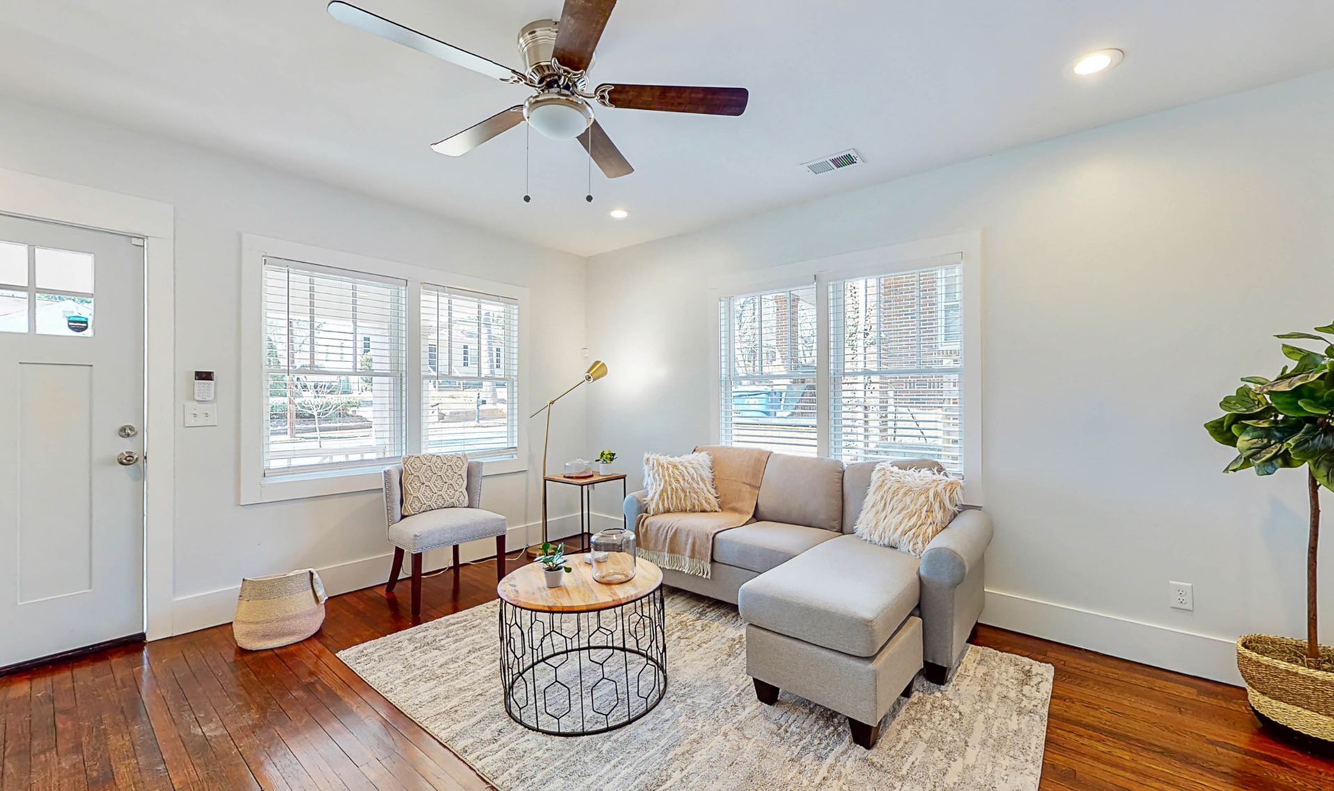 Living room with gray sectional, round coffee table, and windows.