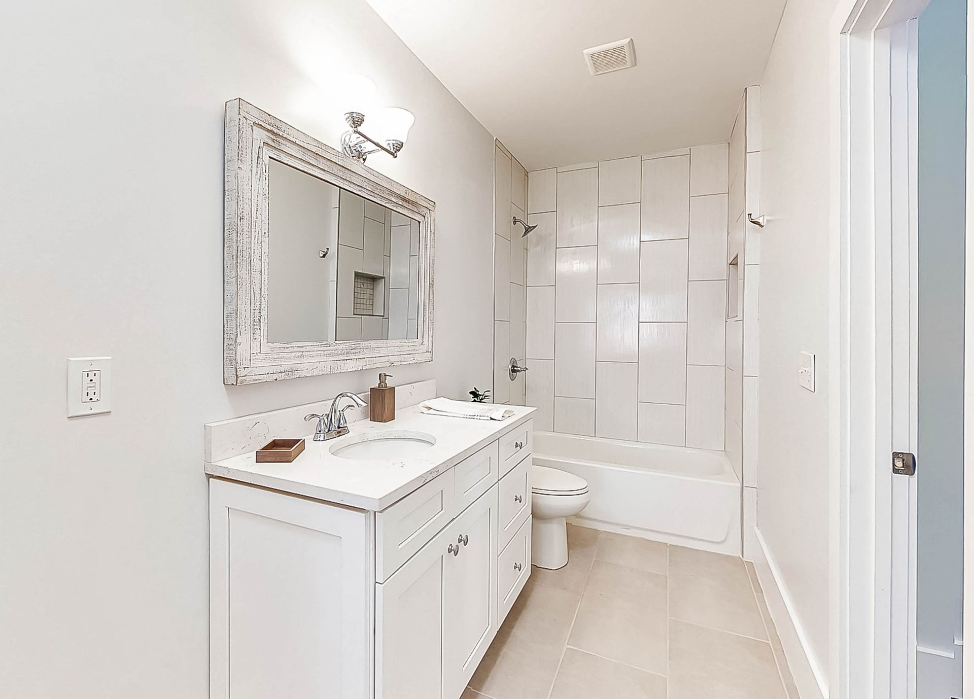 White bathroom with a vanity, mirror, and shower/tub combo.