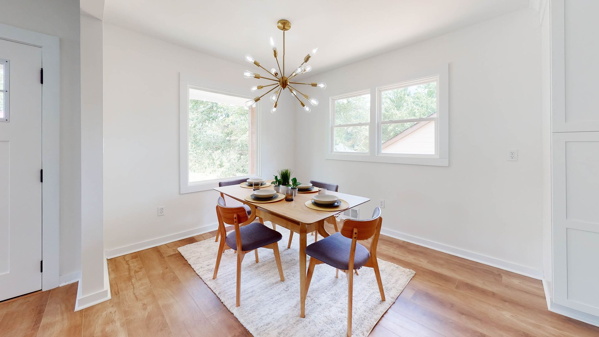 Dining room with wooden table and chairs, chandelier, and windows.