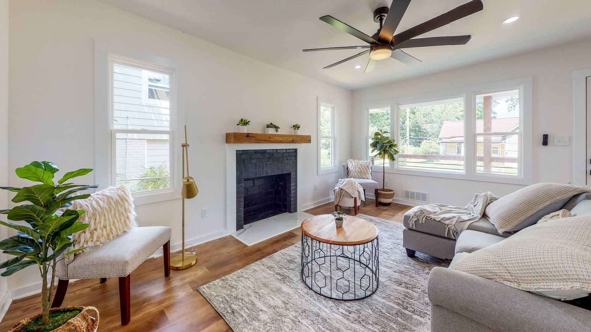 Living room with fireplace, gray sofa, coffee table, and large windows.