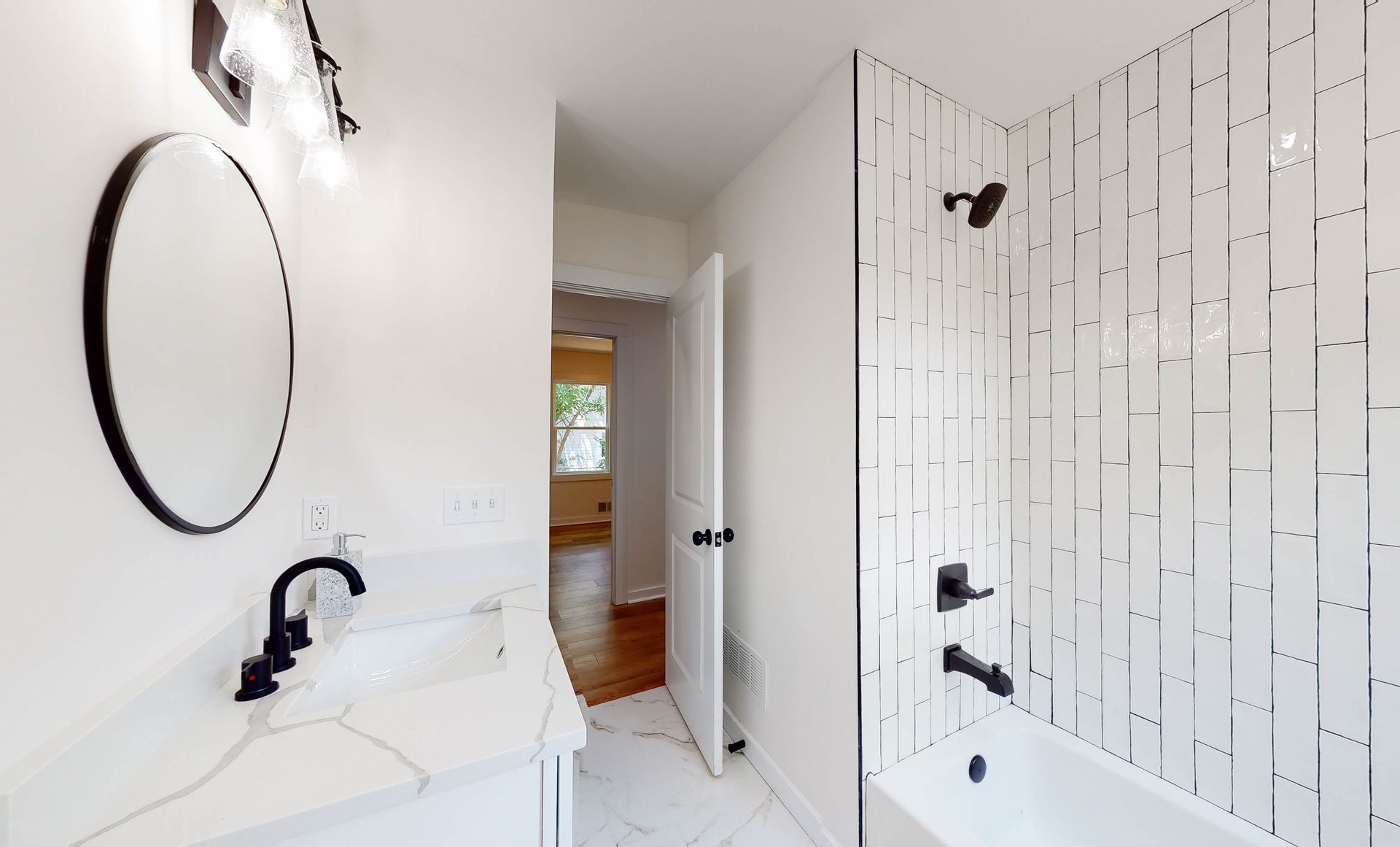 Bathroom with white walls, marble-look floor, black fixtures, and a white tile shower.