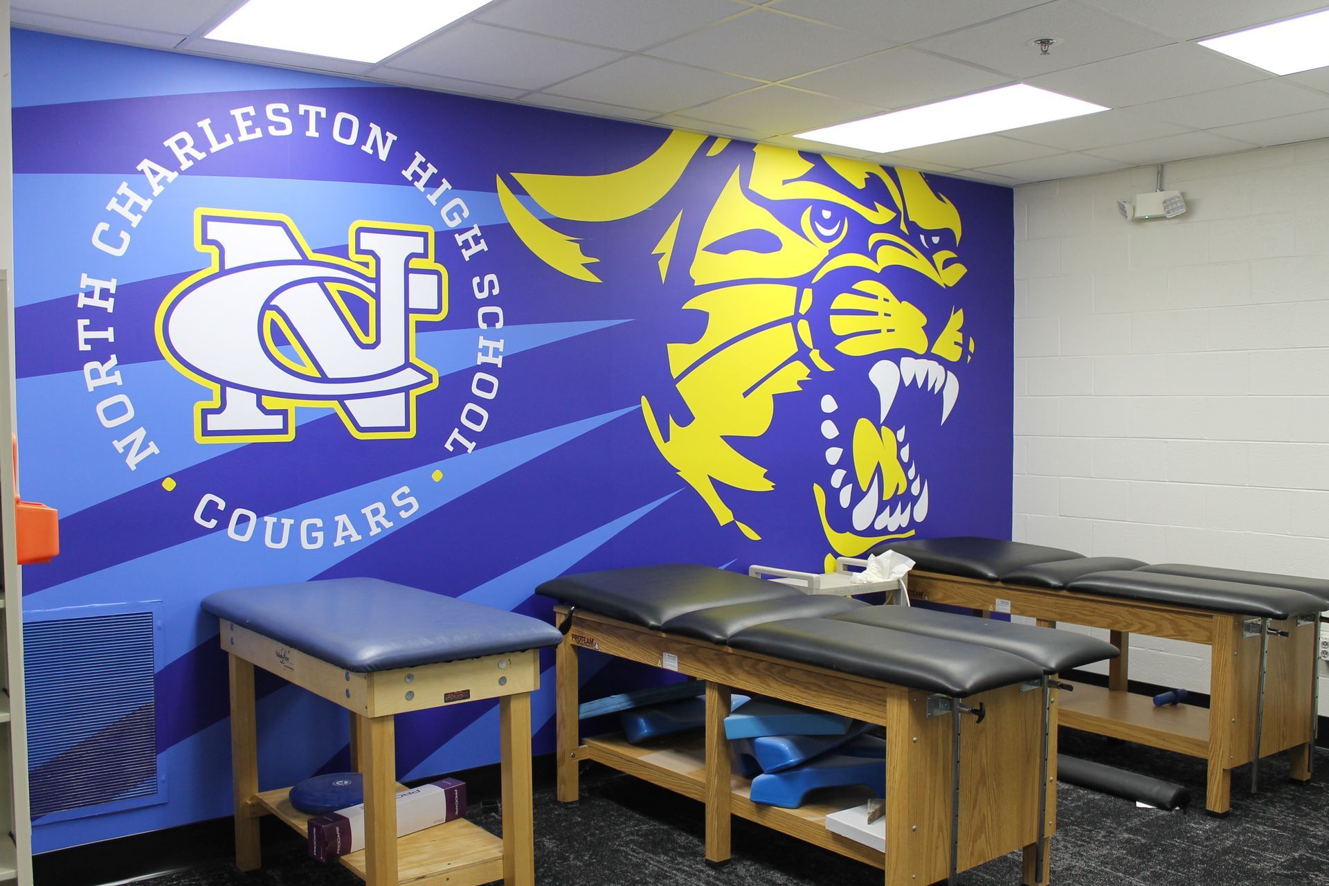 North Charleston High School athletic training room with Cougars logo and treatment tables.