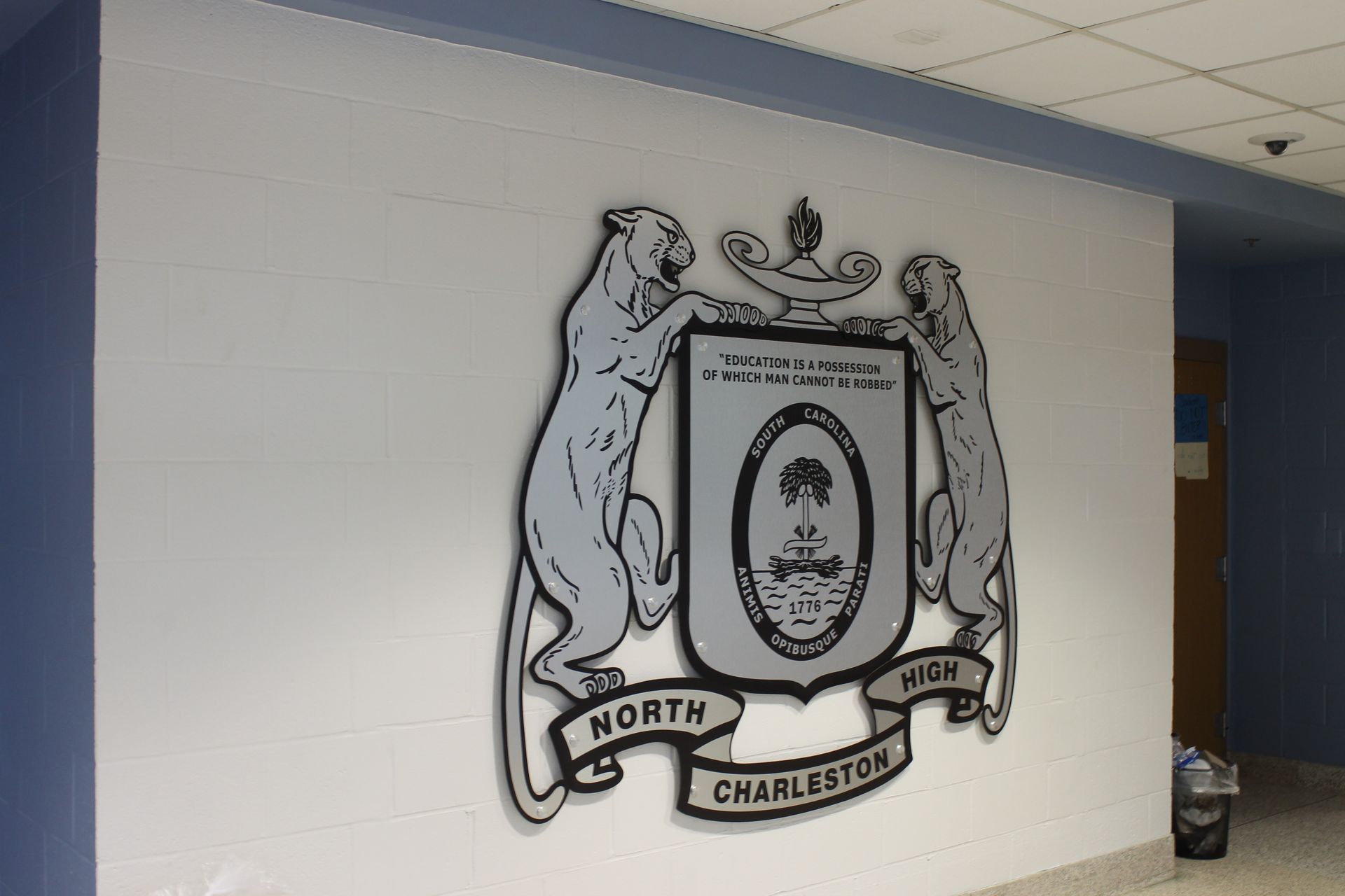 North Charleston High School emblem: two panthers flanking a crest with a palmetto and crescent on a white wall.