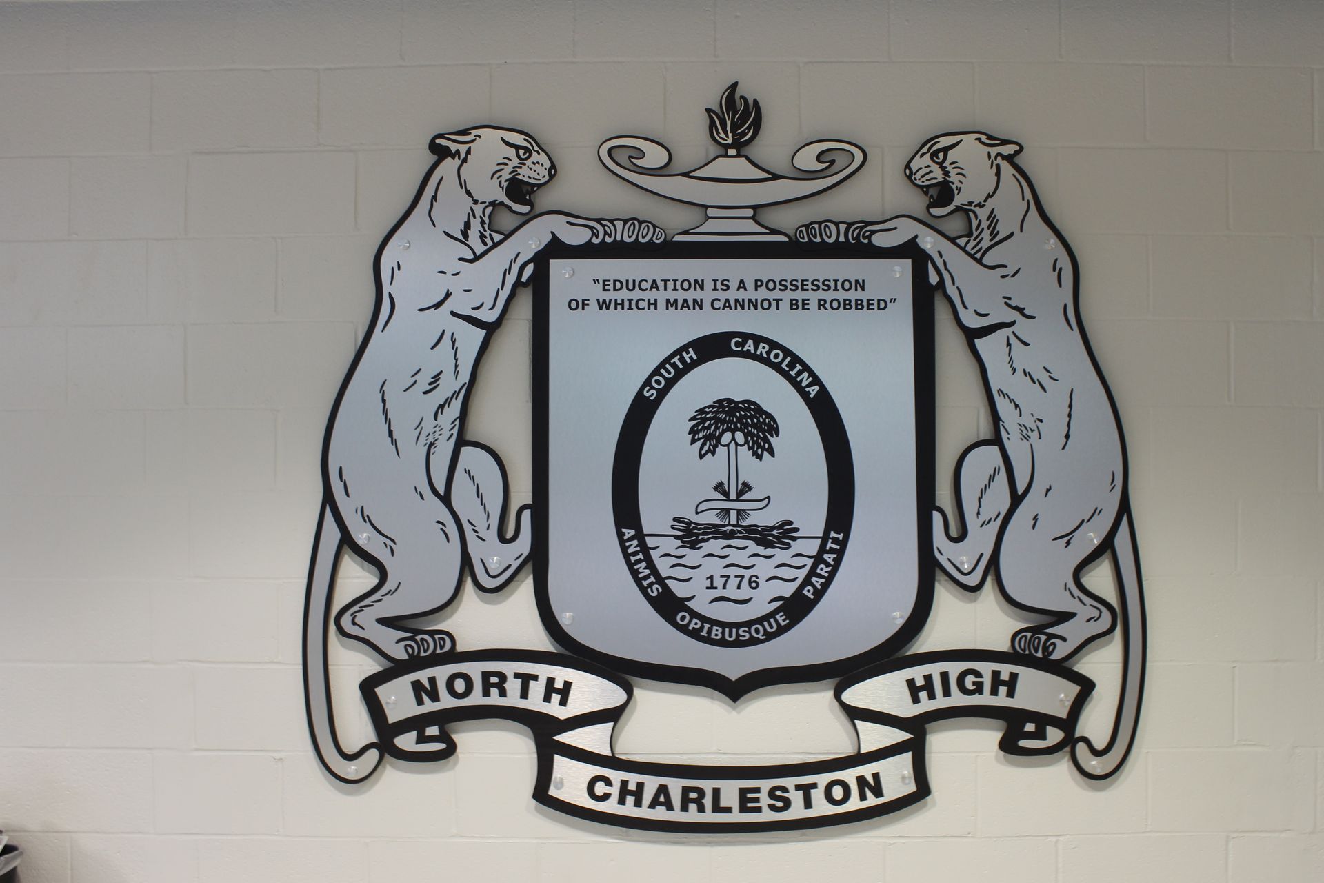 North Charleston High School emblem with cougars flanking a shield with a palmetto tree.