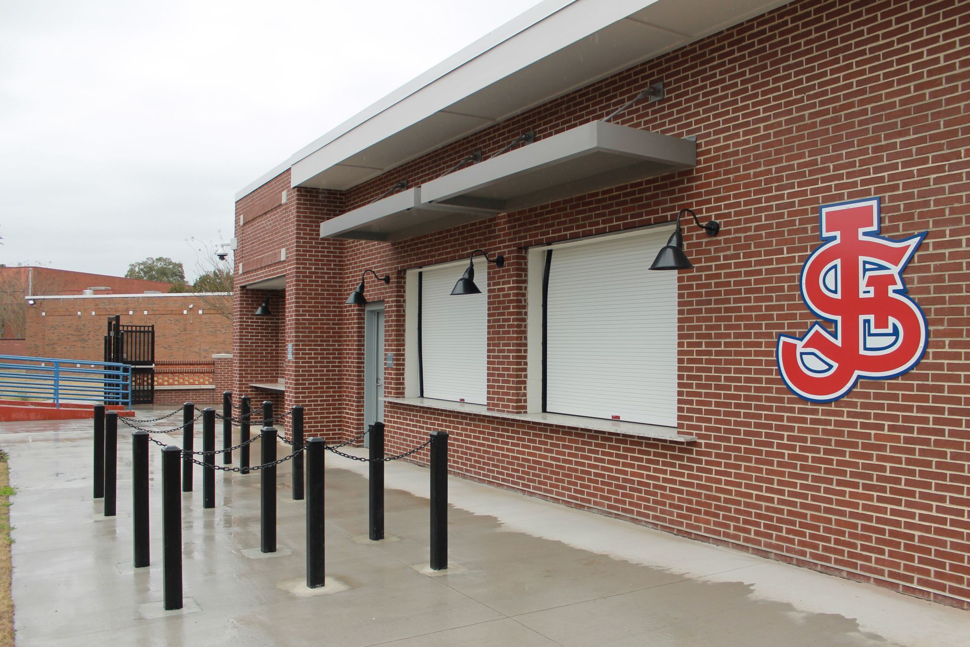 Brick building with closed service windows, awning, SJ logo, and bollards.