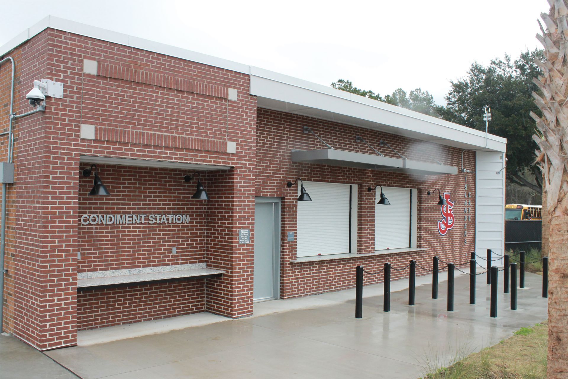 Red brick building with a service window, metal poles, and security cameras.