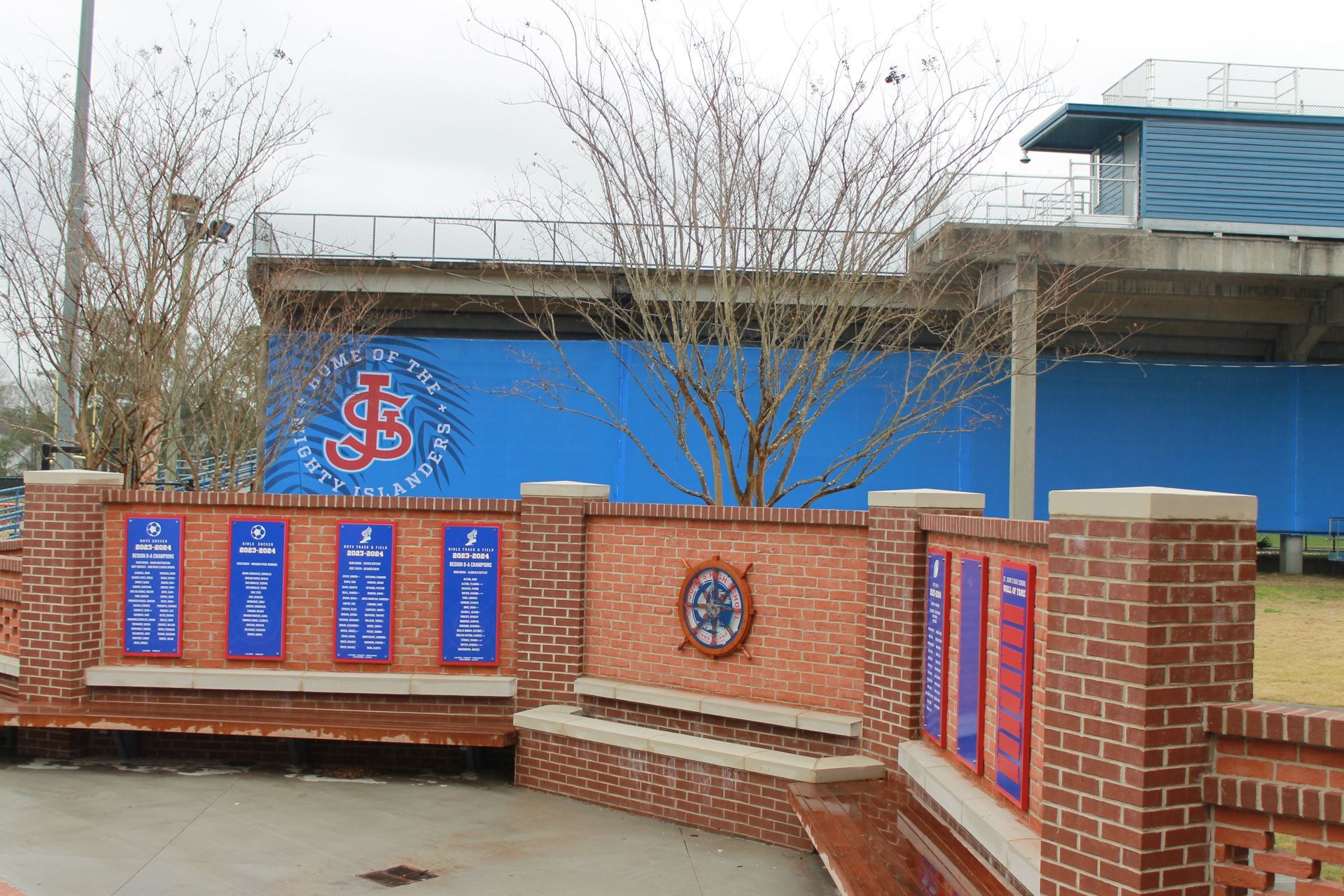 Brick wall with plaques, a bench, and a baseball stadium with a blue backdrop and logo.