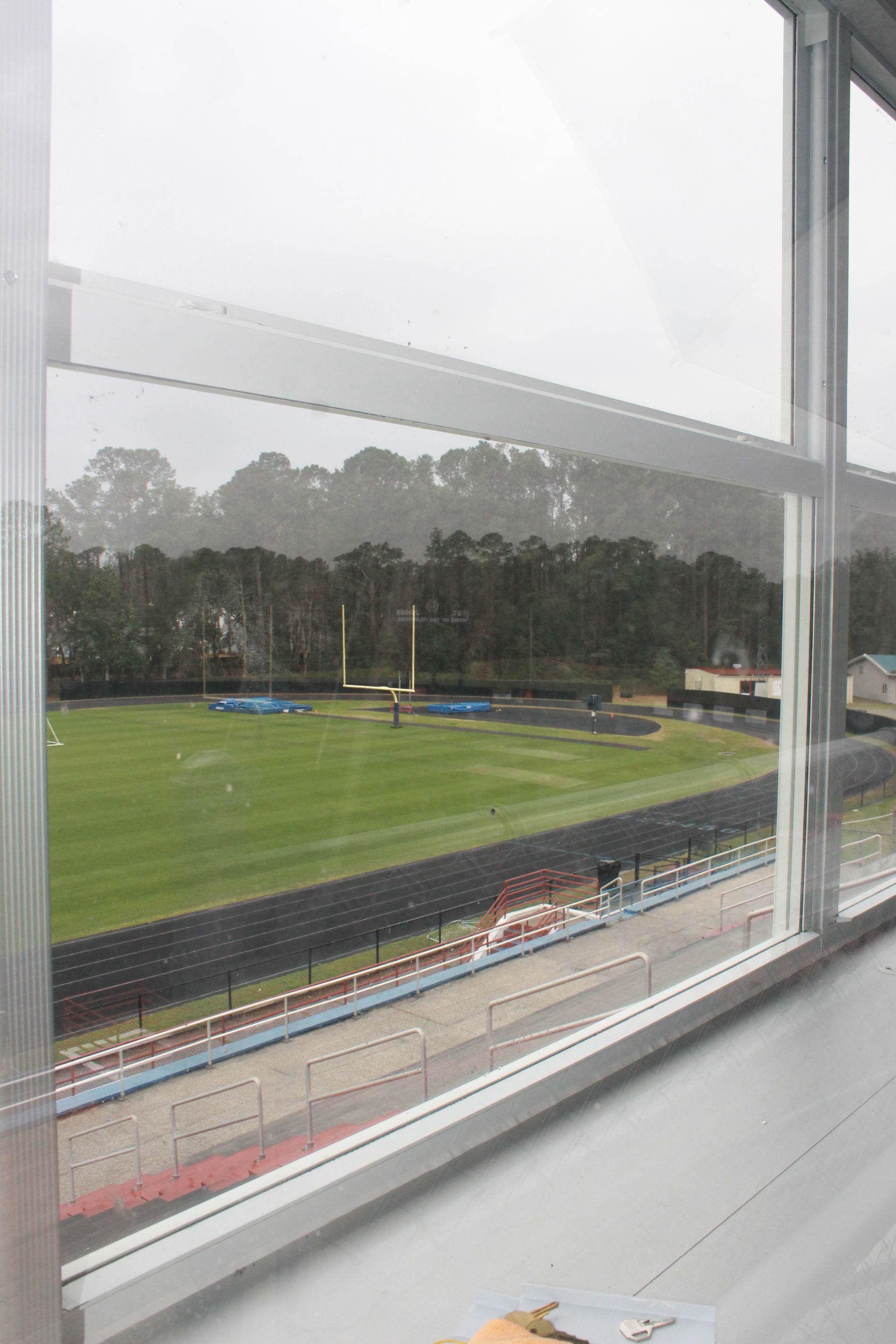 View of a baseball field and track through a window on a rainy day.