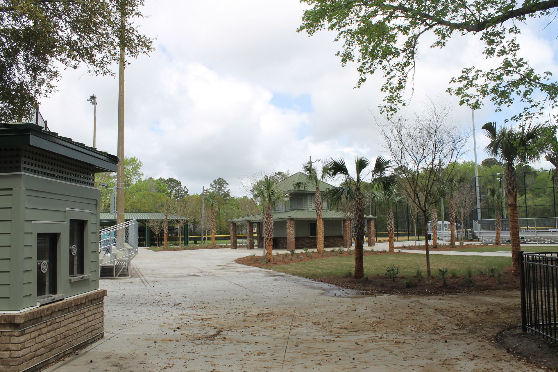 Entrance to a park with a concession stand and covered seating; palm trees and light poles.