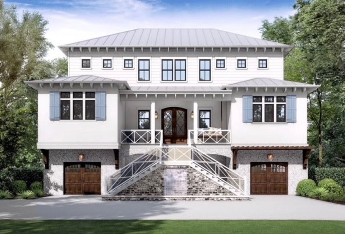 White beach house with light blue shutters, metal roof, and stone base; two-car garage.