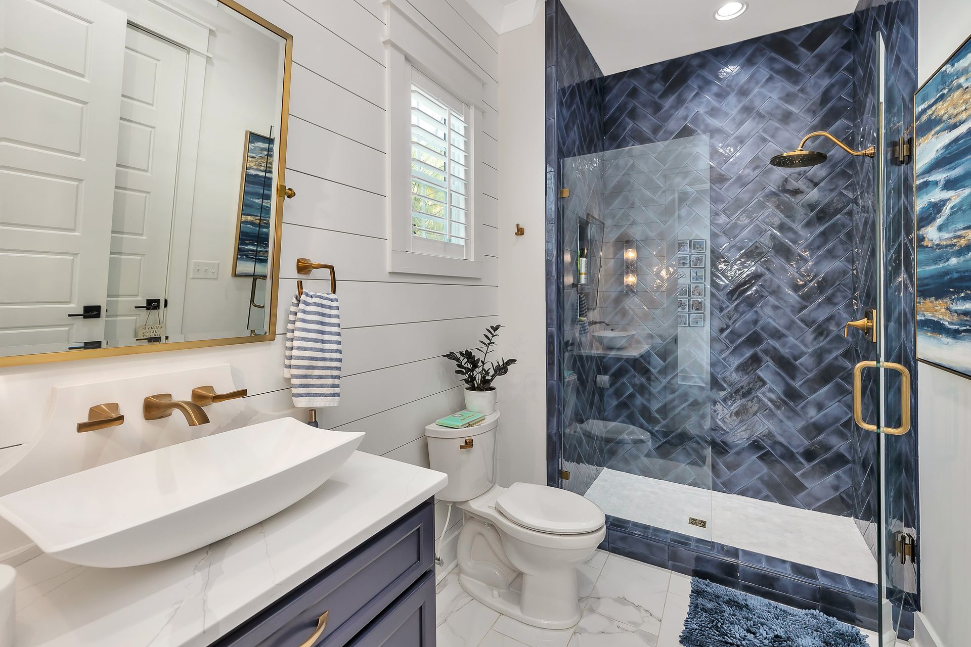 Bathroom with a blue tiled shower, white sink, and gold fixtures.
