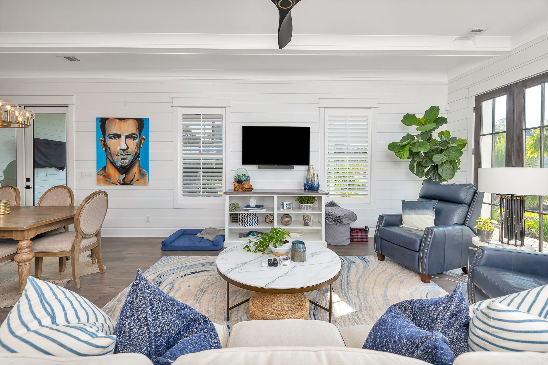 Living room with white walls, TV, blue sofa, and art.