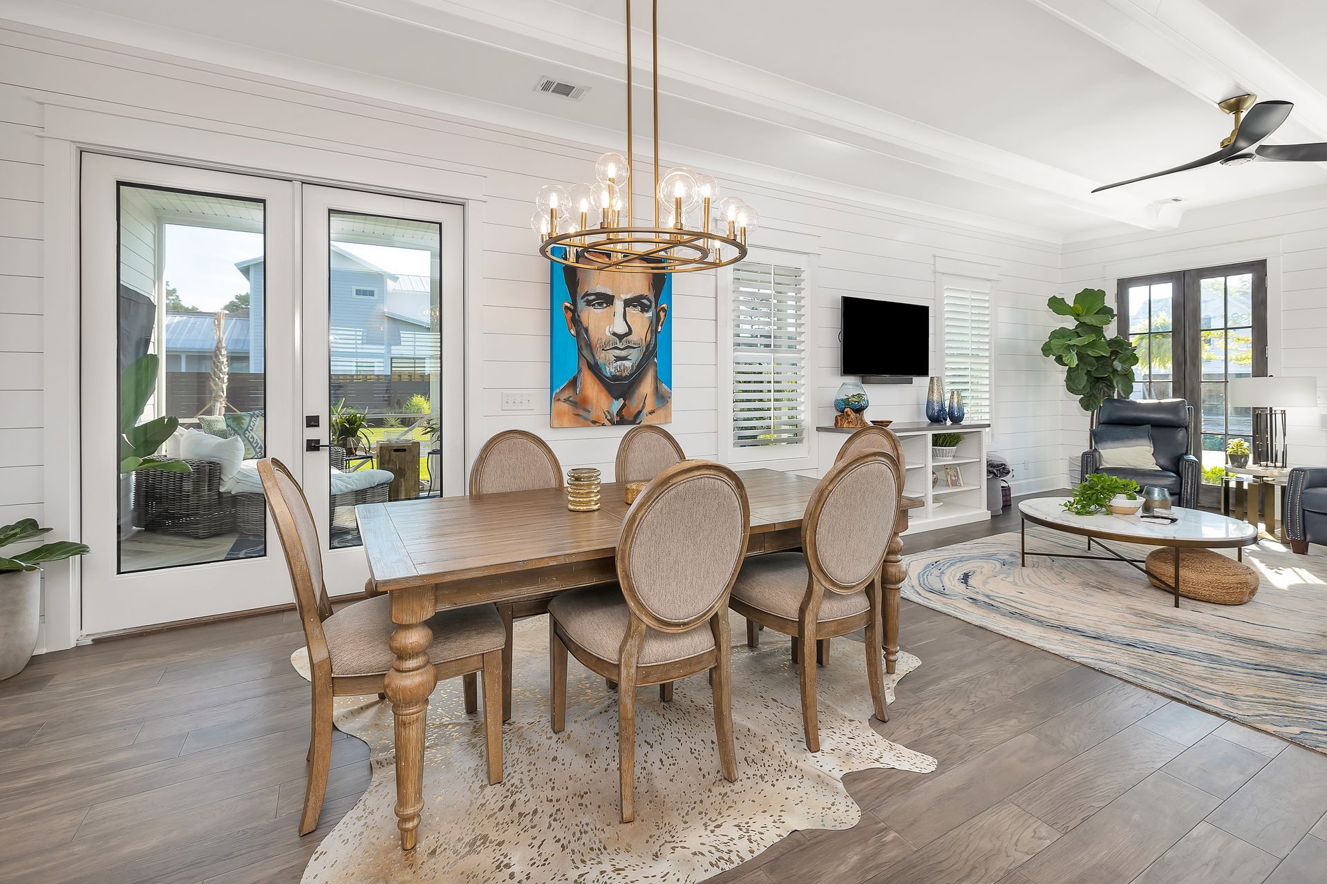Dining room with table, chairs, art, and light fixture, in a bright space with a cowhide rug.