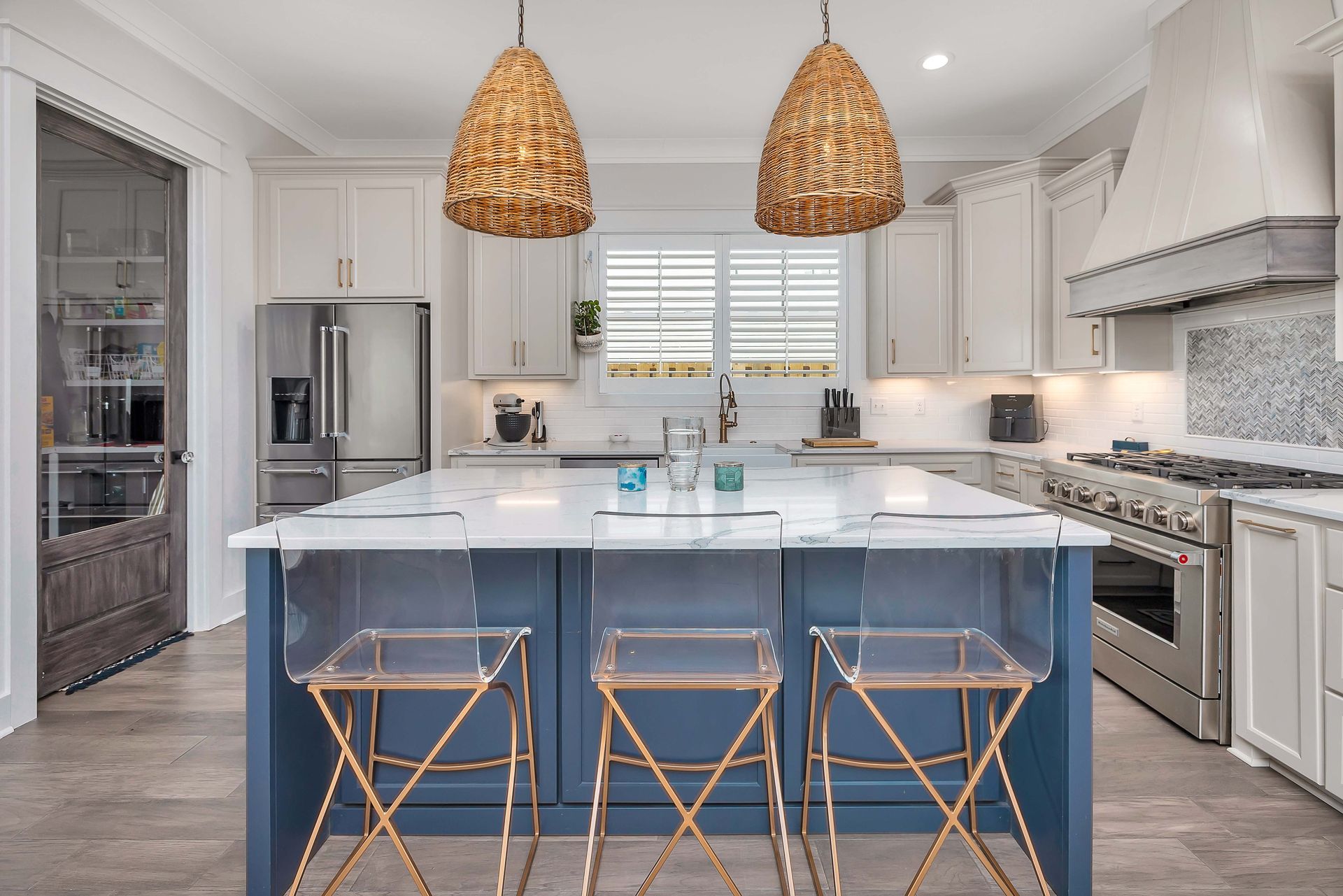 Modern kitchen with blue island, white cabinets, stainless steel appliances, and woven pendant lights.