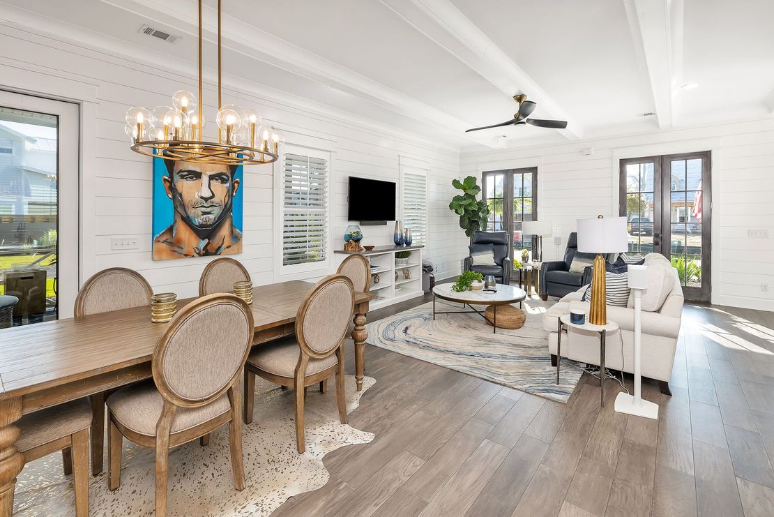 Dining and living room with table, art, sofa, and hardwood flooring.