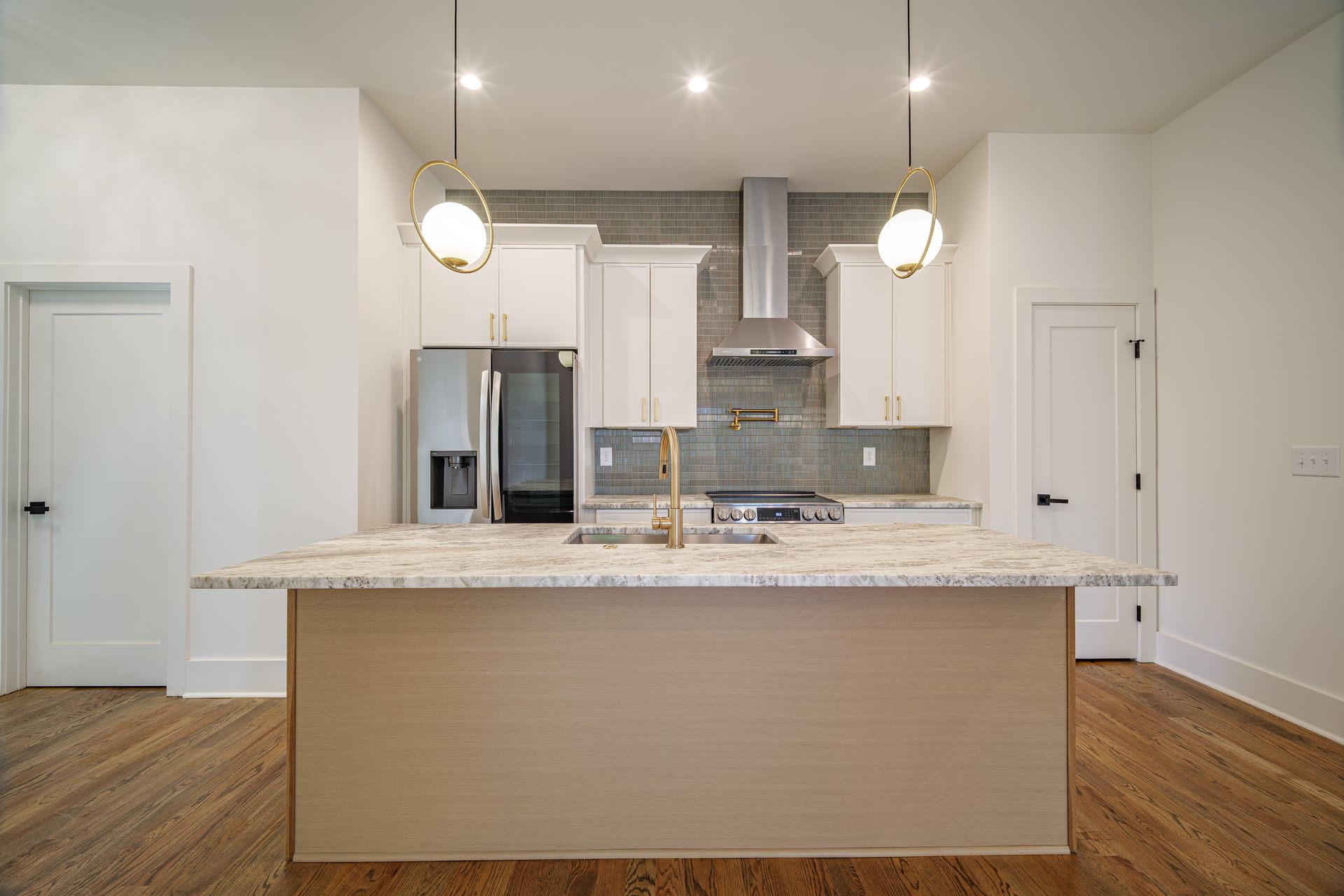 Modern kitchen with island, stainless steel appliances, and white cabinets.