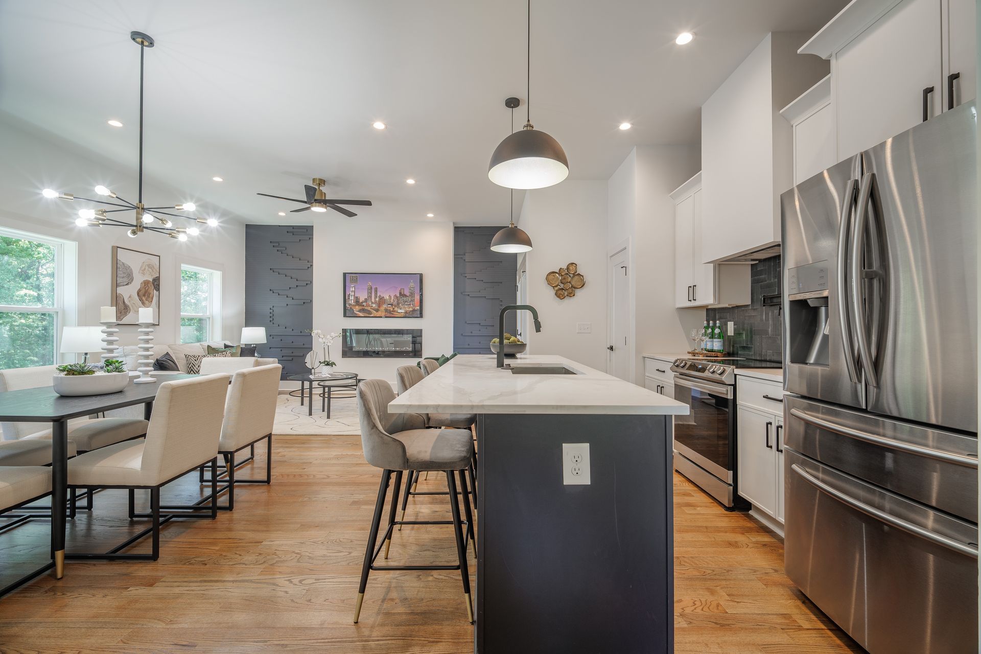 Open-concept kitchen and dining area with stainless steel appliances, dark island, and modern decor.