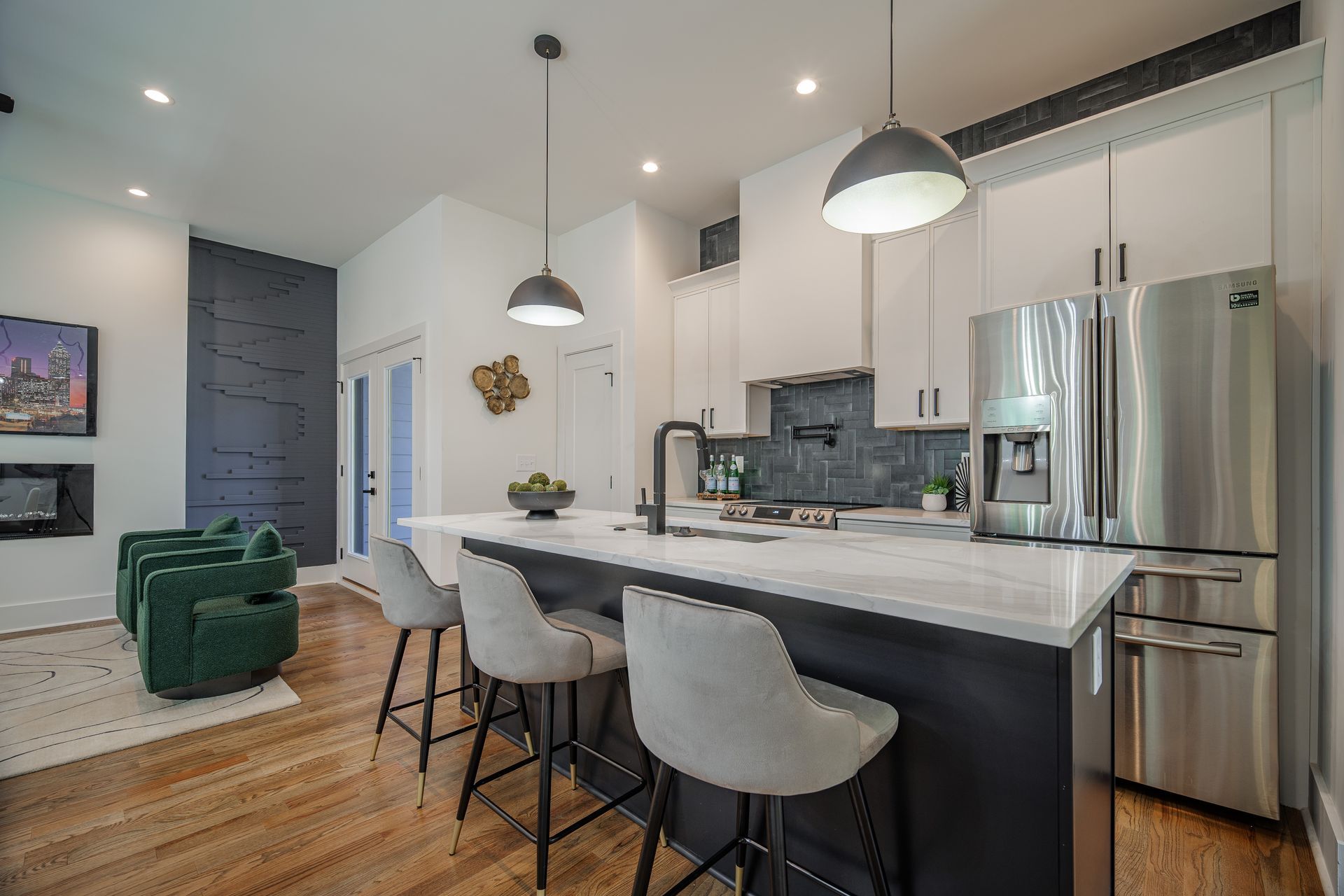 Modern kitchen with island, stainless steel appliances, white and gray cabinetry, and three barstools.