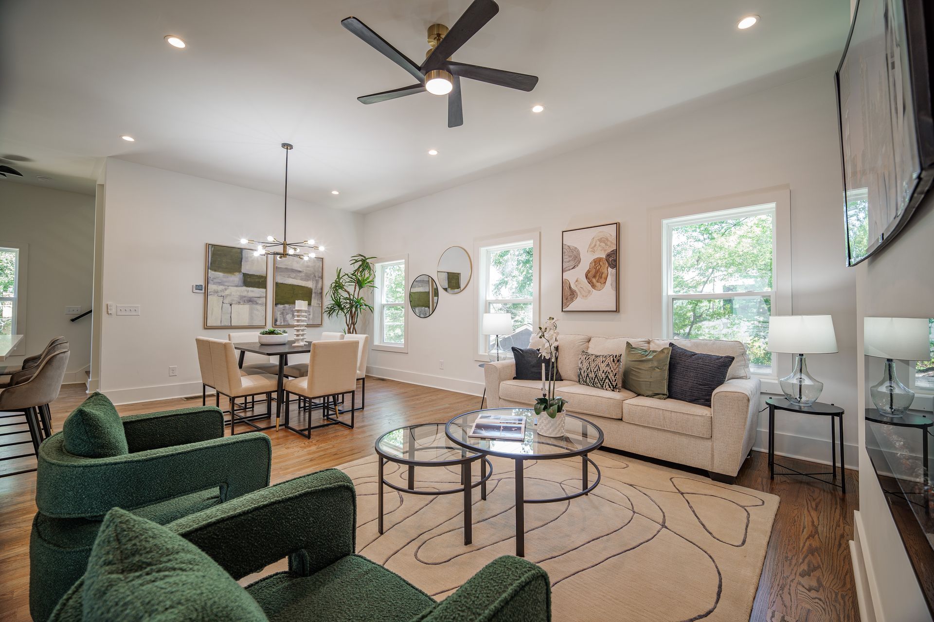 Living room with white walls, dark wood floors, modern furniture, and a round dining table.
