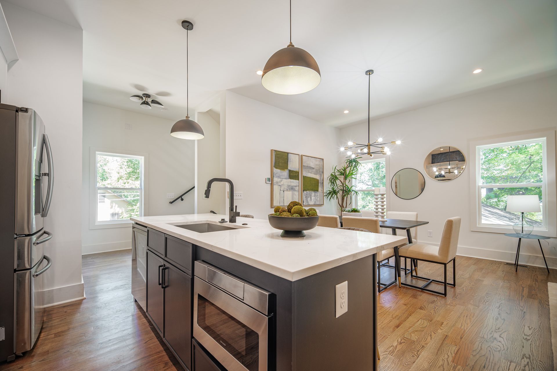 Modern kitchen with island, stainless steel appliances, and dining area with round mirrors.