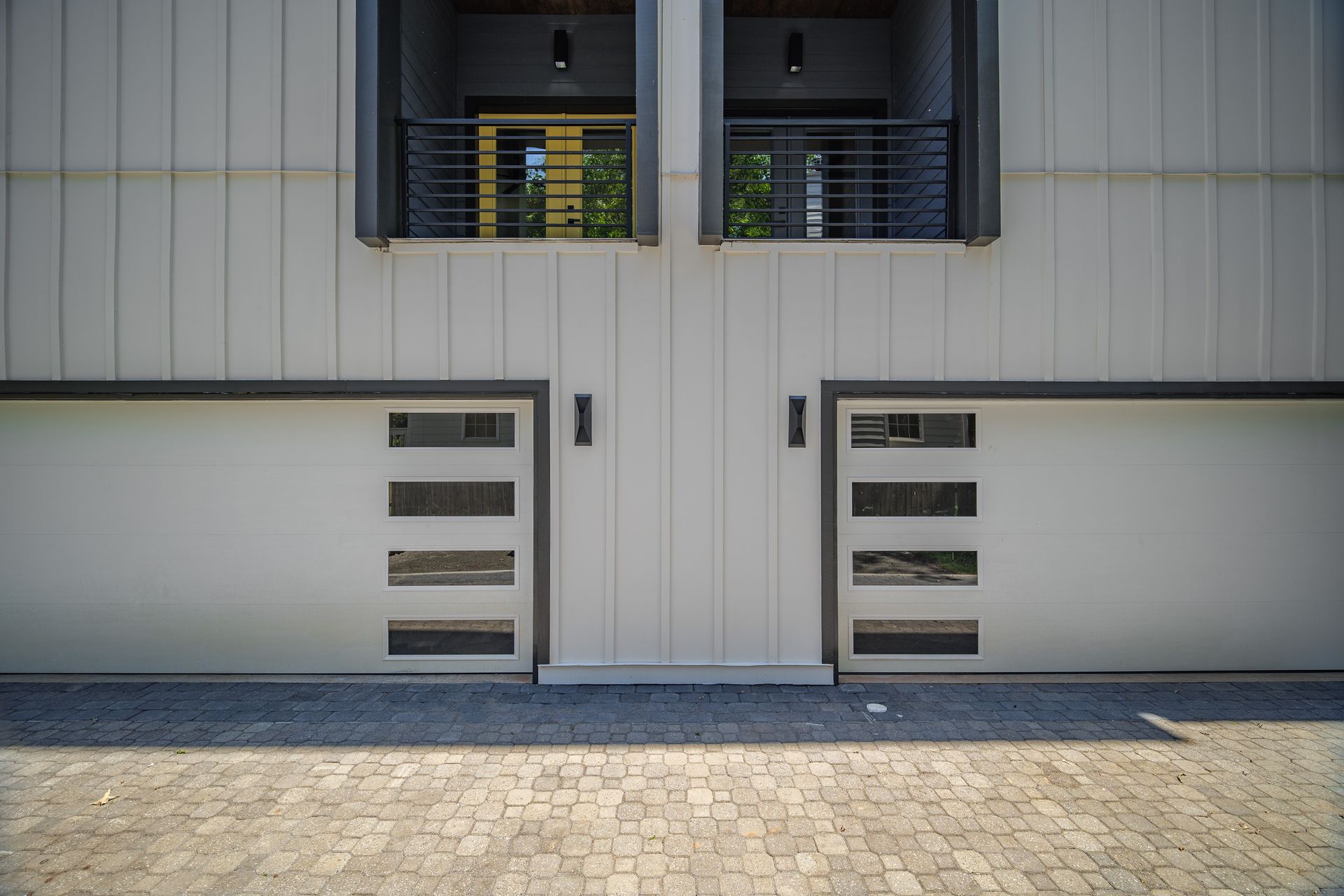 Modern building facade with two garage doors and balconies above.