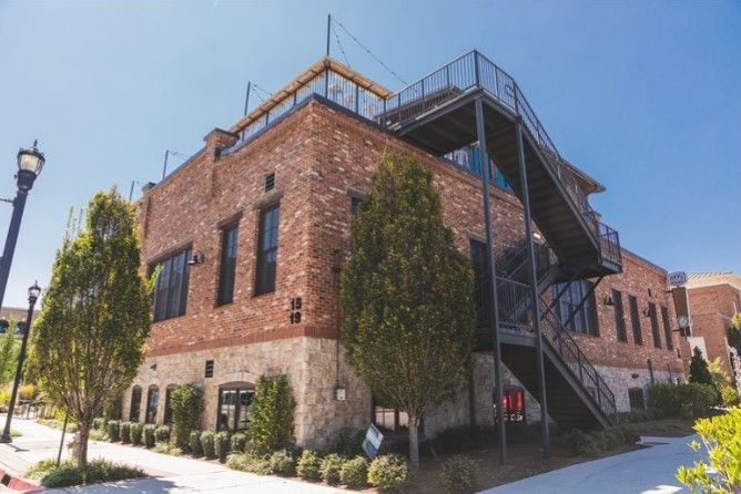 Brick building with black metal fire escape, rooftop deck, and several windows.