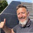 Kaine standing beside solar panels installed on a roof