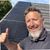 Kaine standing beside solar panels installed on a roof