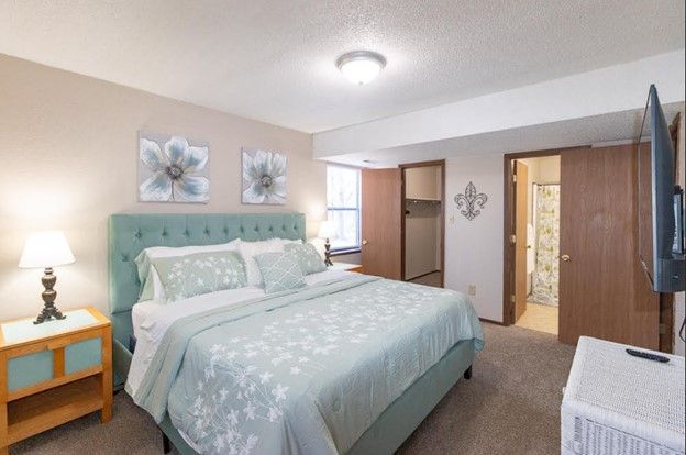 Bedroom with a queen bed, teal bedding, and two flower paintings above the headboard.