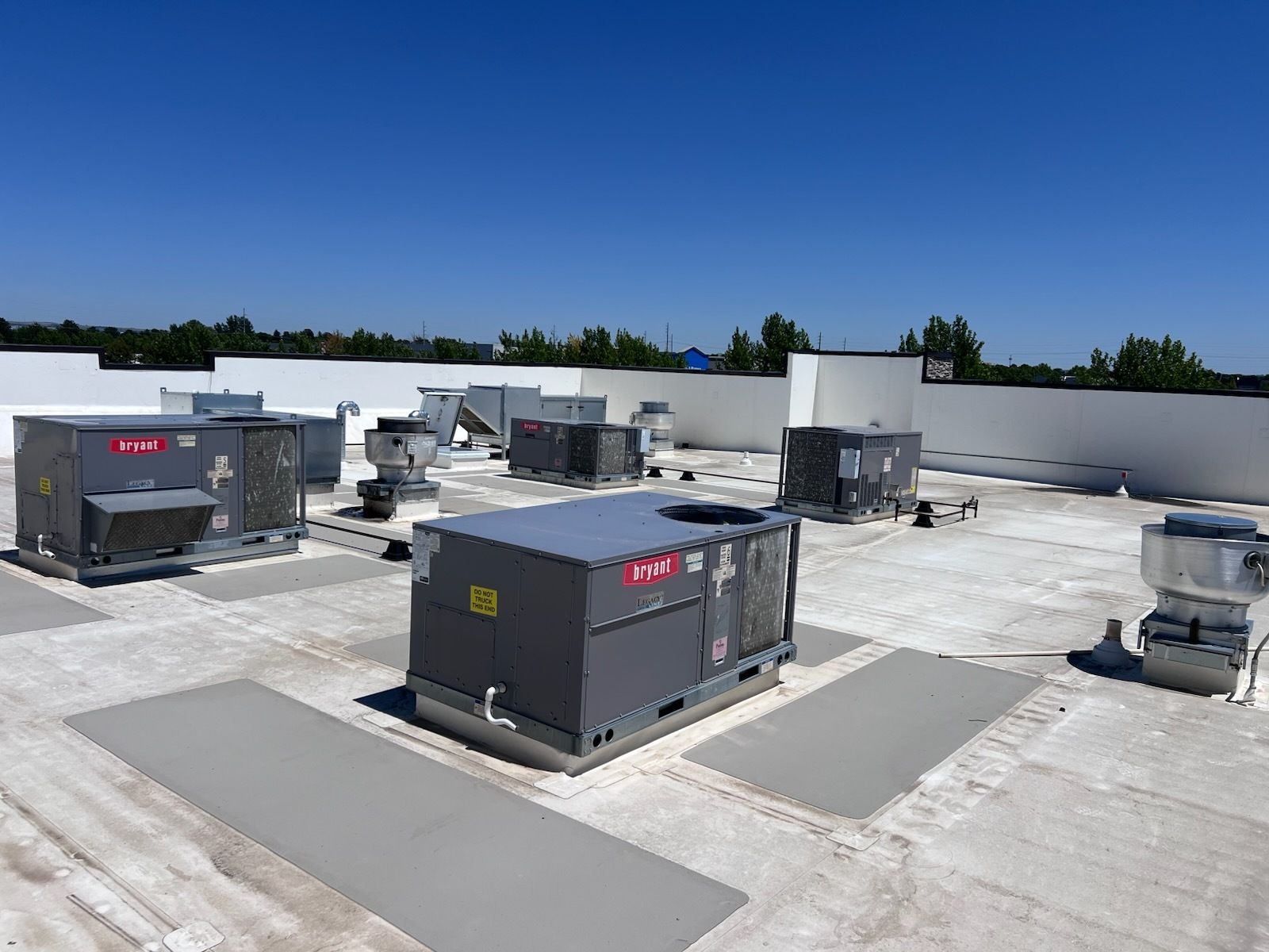 Rooftop view of several large, gray HVAC units against a blue sky.
