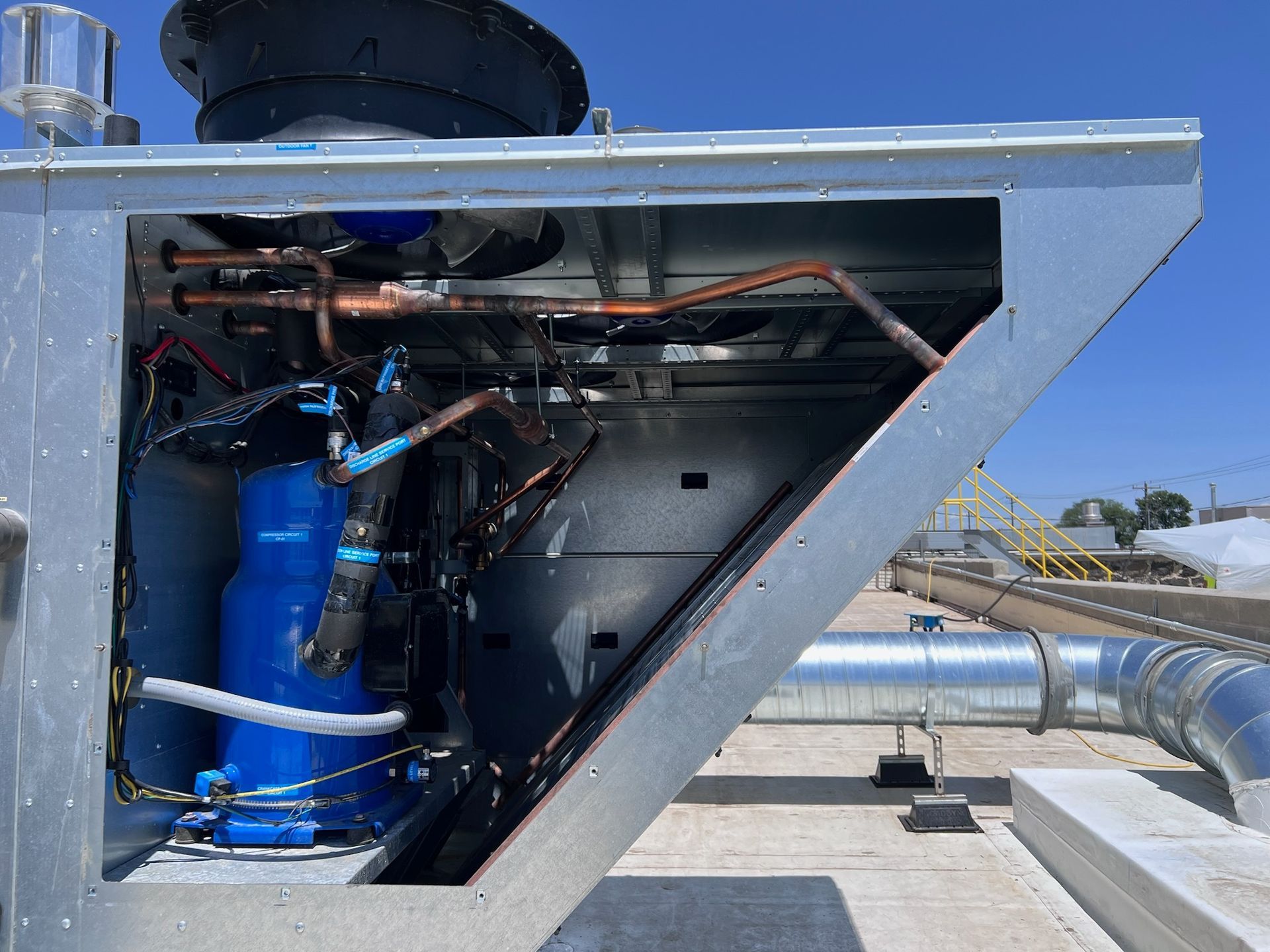 Blue HVAC compressor and copper tubing inside a rooftop unit.