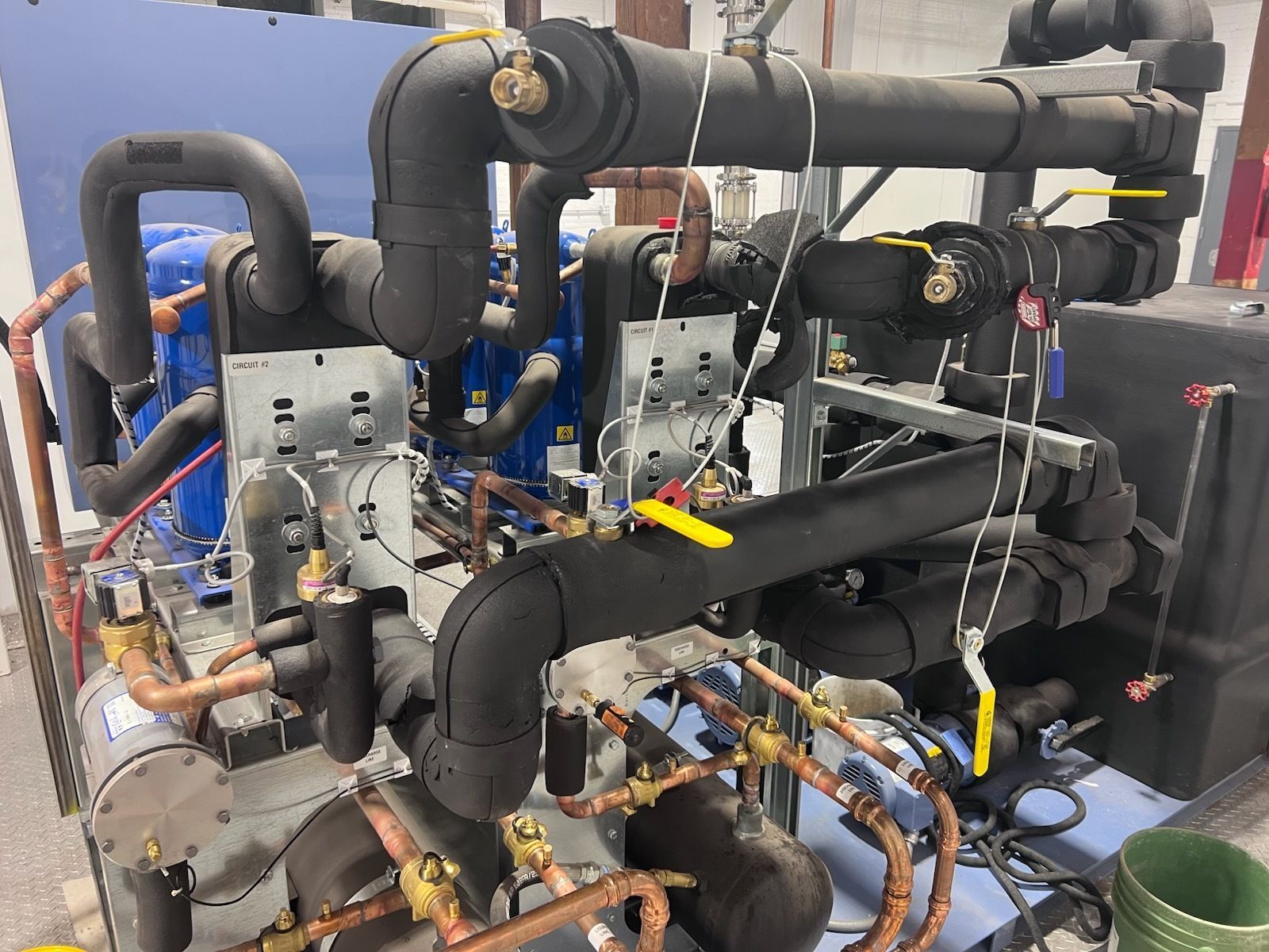 Industrial chiller system with insulated pipes and copper tubing, indoors.