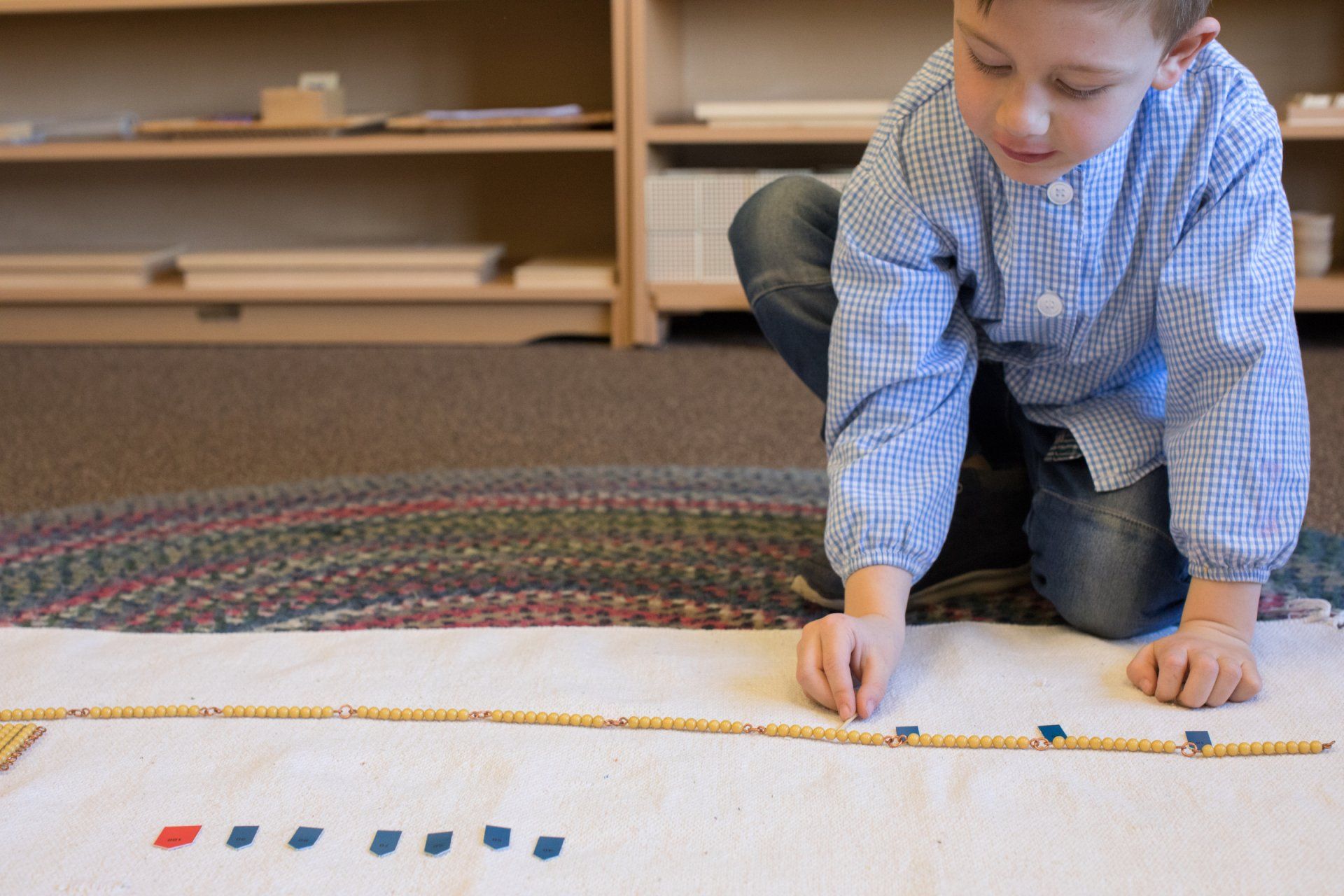 Child working with the Montessori golden beads
