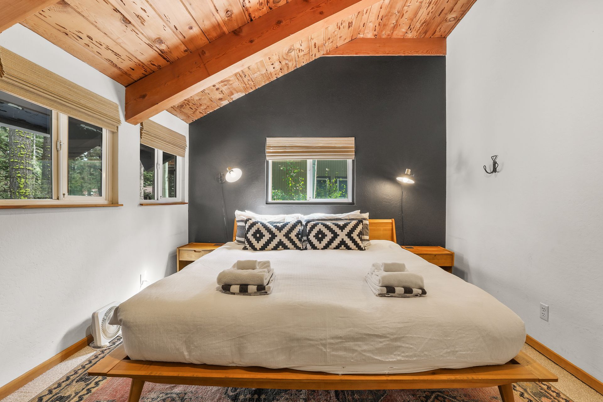 Cozy bedroom with vaulted wood ceiling, gray accent wall, and a bed with patterned pillows