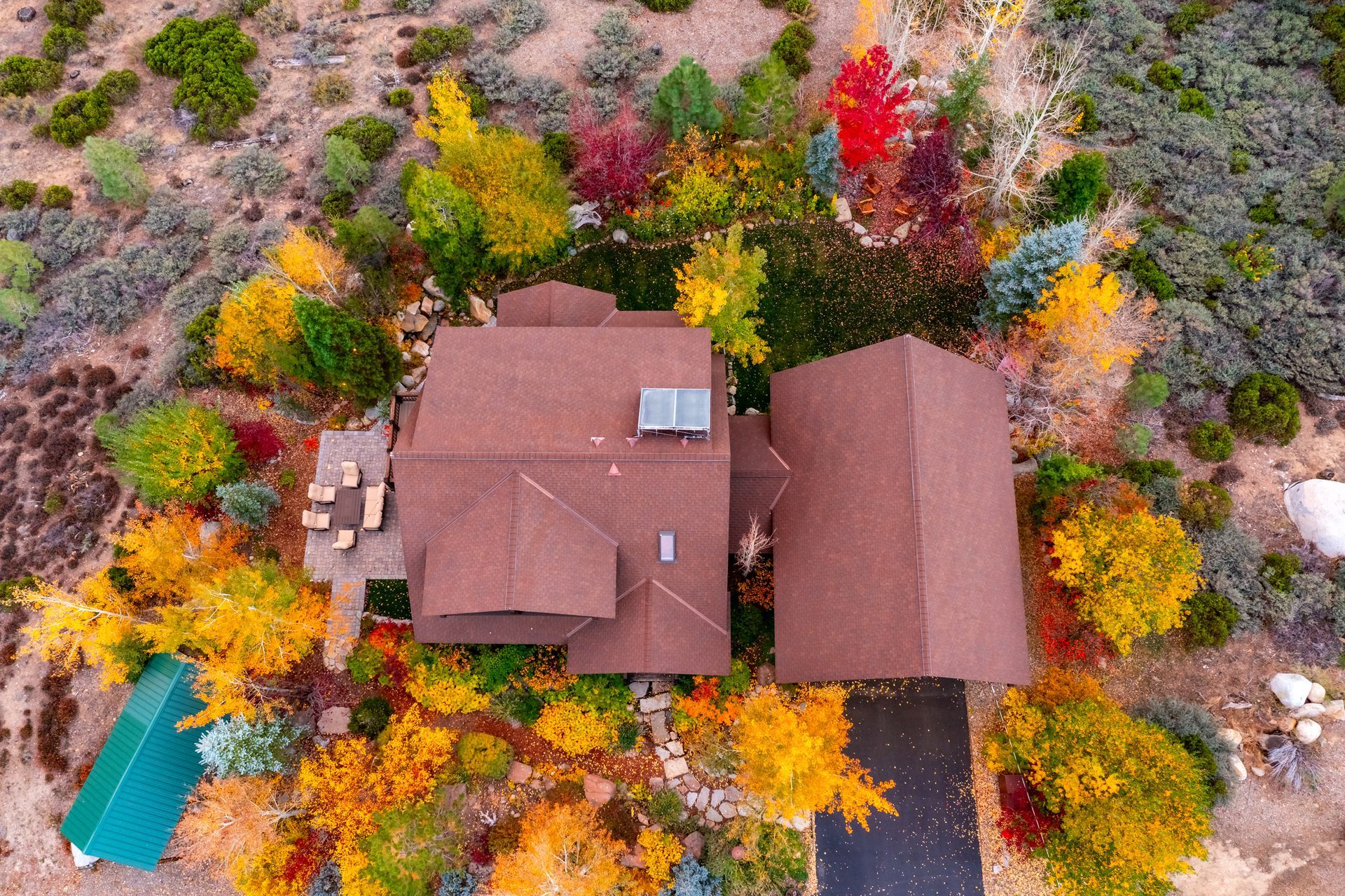 Aerial view of a house surrounded by colorful autumn trees and shrubs.