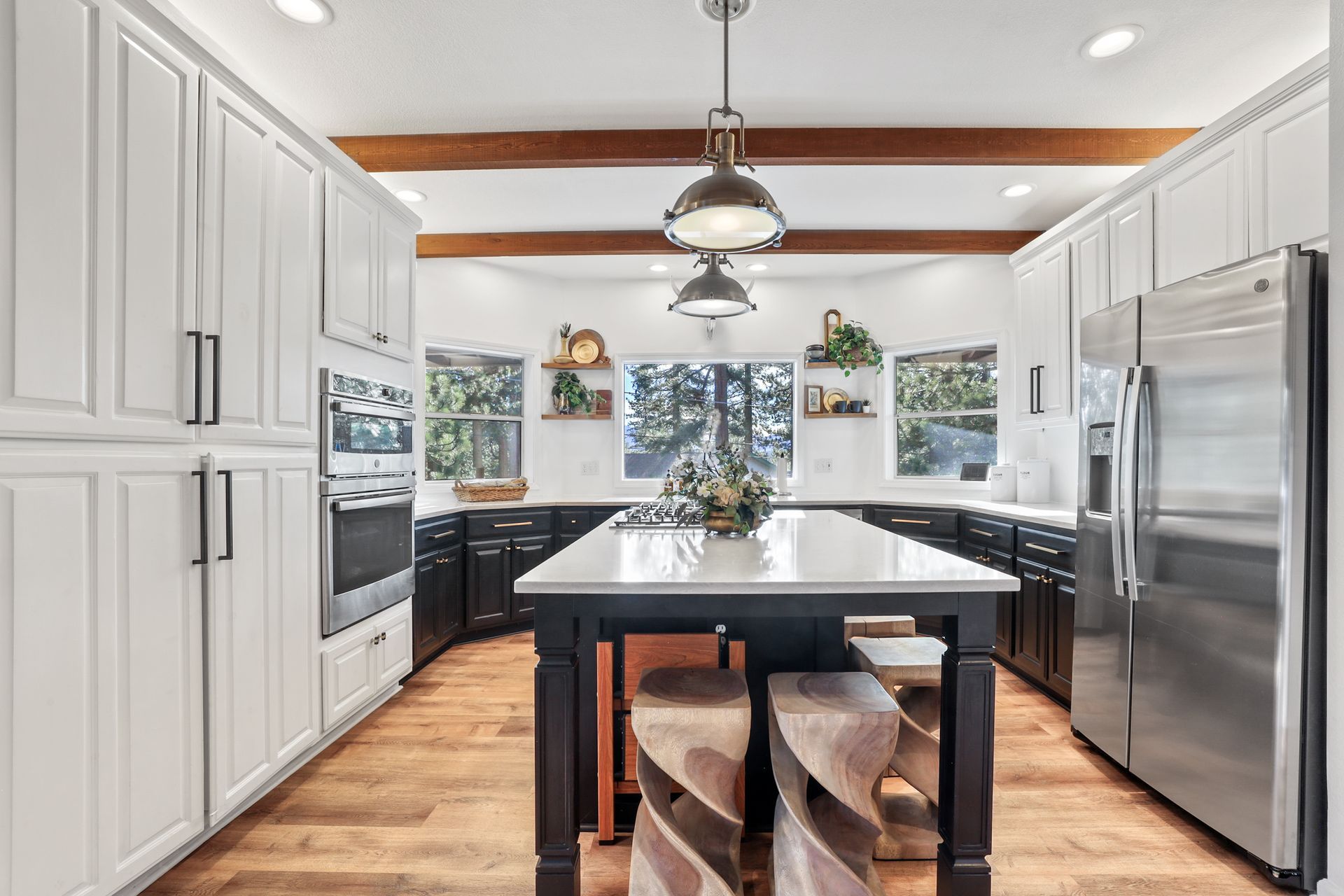 Bright modern kitchen with white cabinets, stainless steel appliances, wood floors, and a black island centerpiece