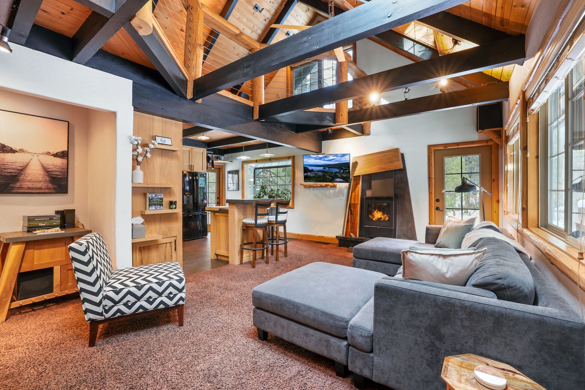 Cozy living room with gray sectional, wood beams, fireplace, and warm modern decor