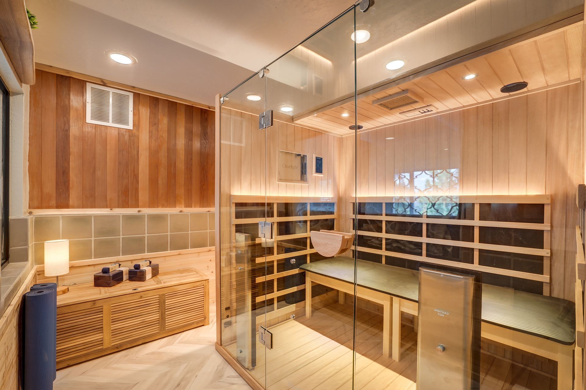 Modern sauna room with wooden benches, glass walls, and soft warm lighting