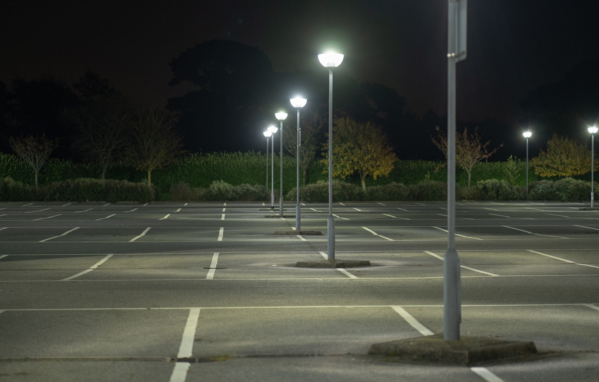 Empty parking lot at night, lit by rows of streetlights.