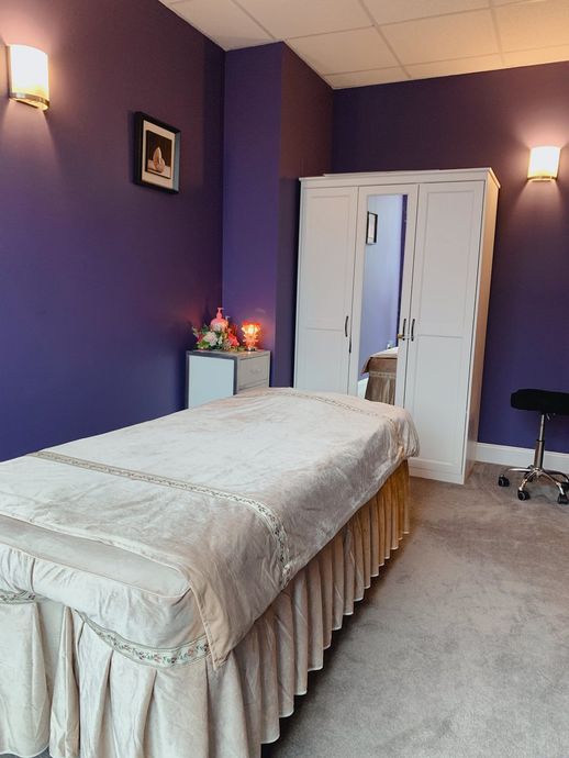 Purple bedroom with a single bed, bedside lamps, a dresser, and an open doorway.