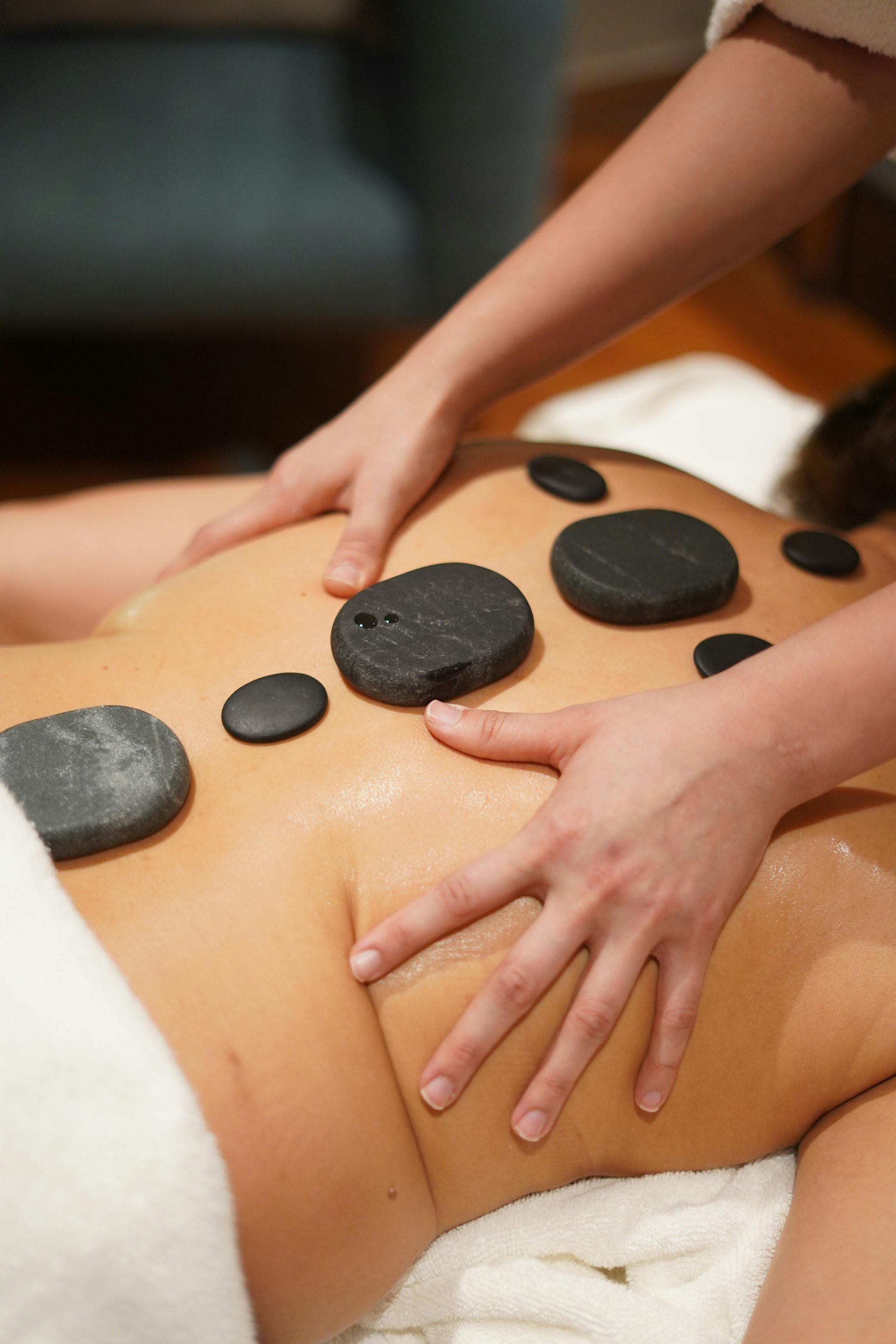 Person receiving a hot stone massage with black stones on their back