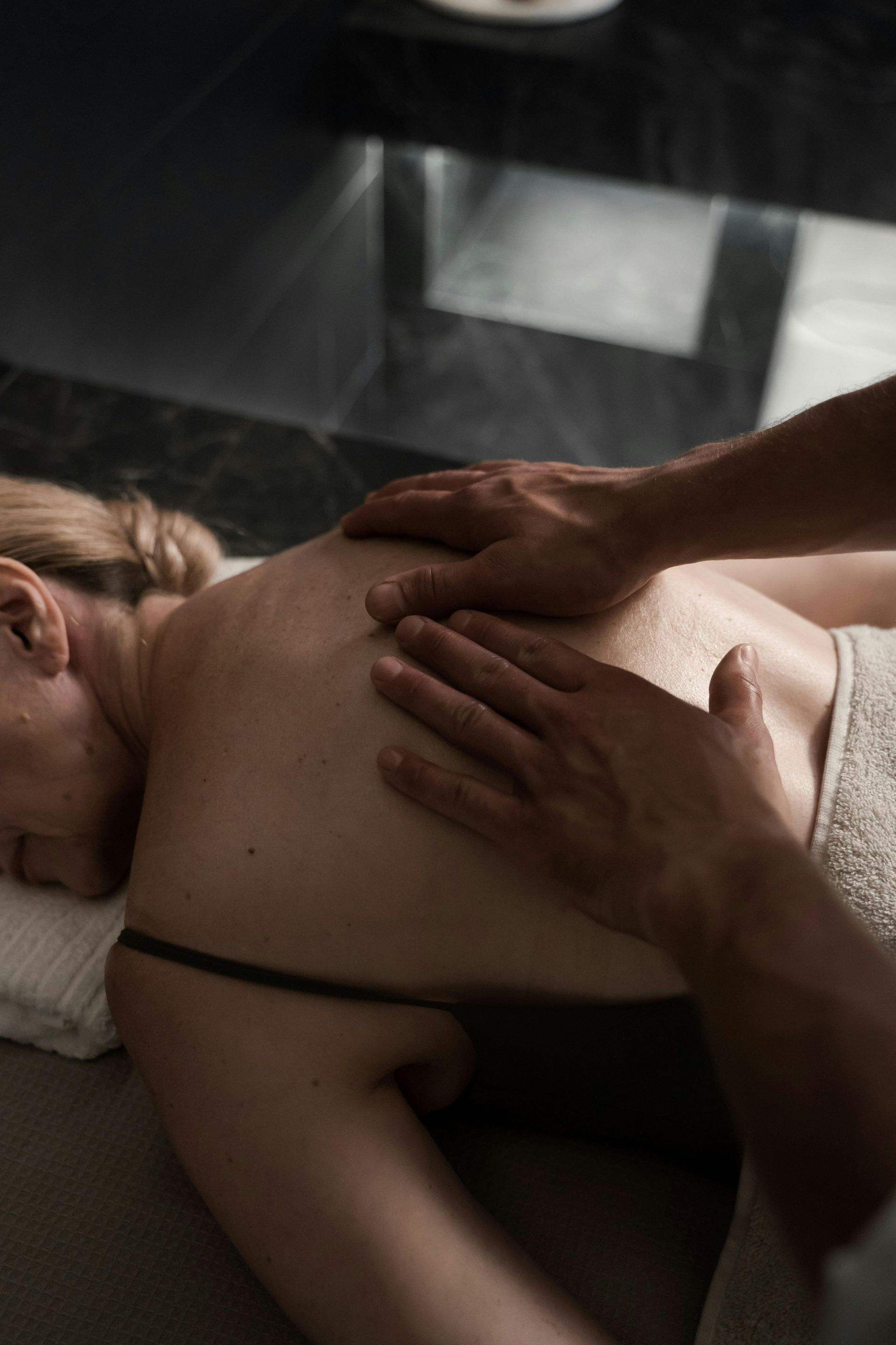 Hands kneading a person’s bare back during a spa massage on a treatment table