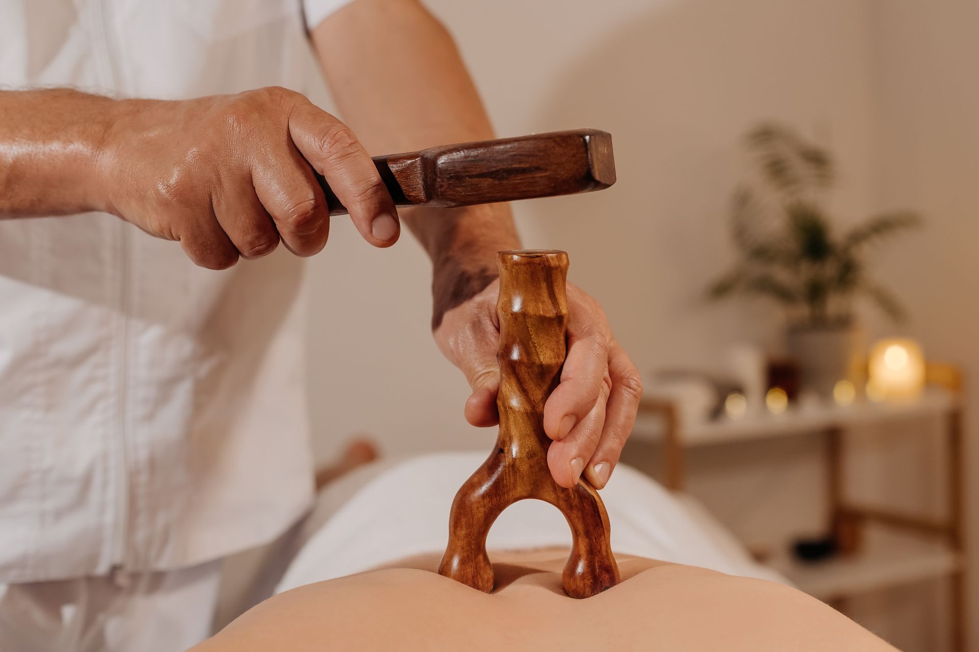 Person using a wooden gua sha tool on a back or leg in a spa setting