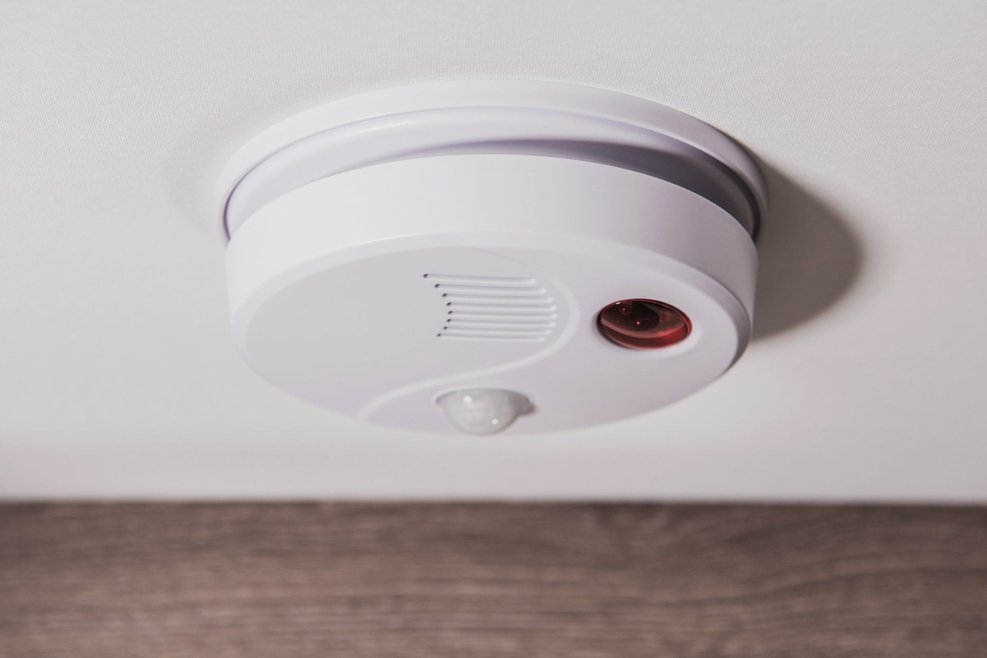 Airbnb listing's interior features a white smoke detector with a red light, ensuring fire safety.