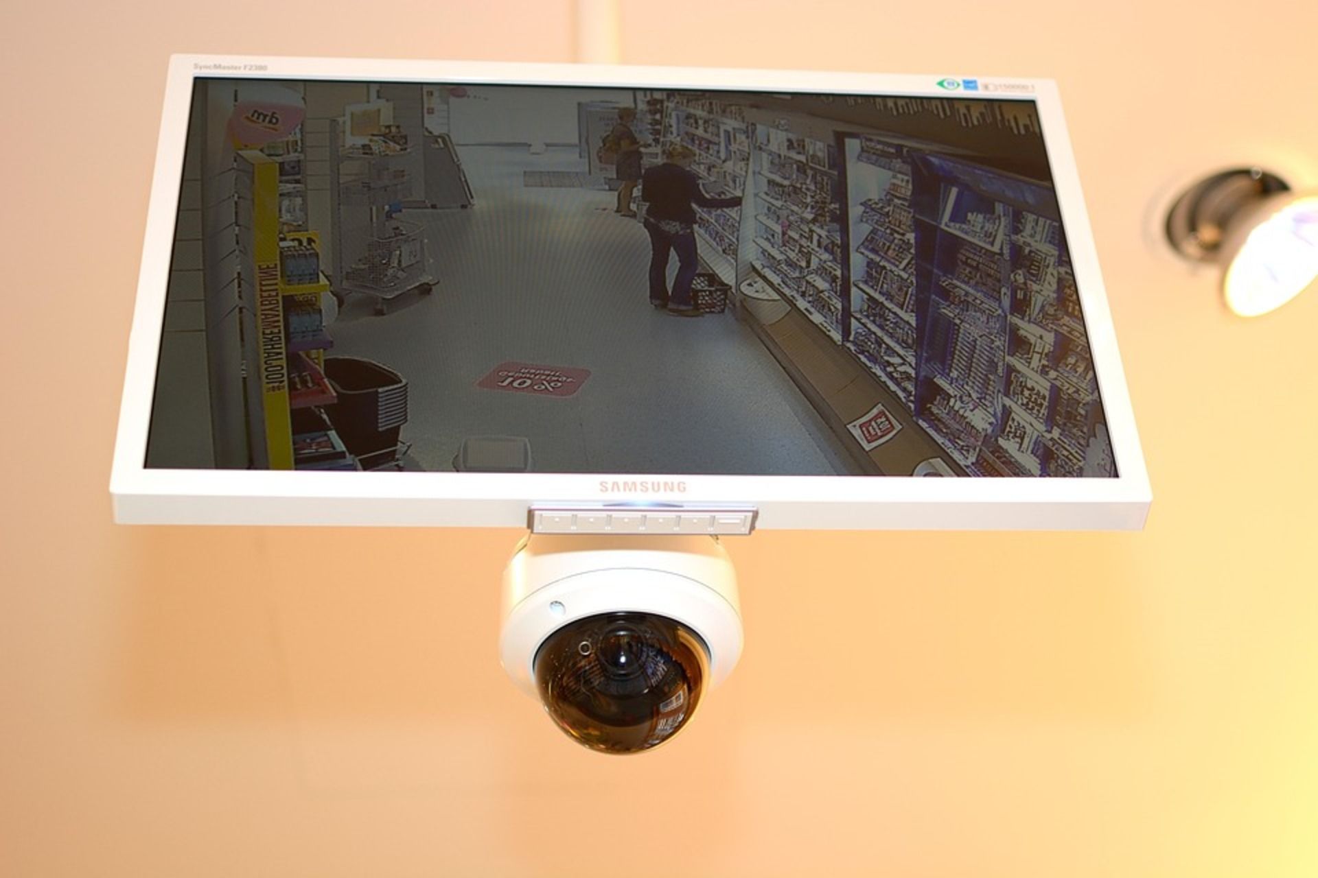 A CCTV camera and display mounted on a supermarket ceiling