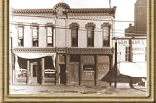 Sepia-toned historic storefronts with awnings and a sign reading “Clean Goods”