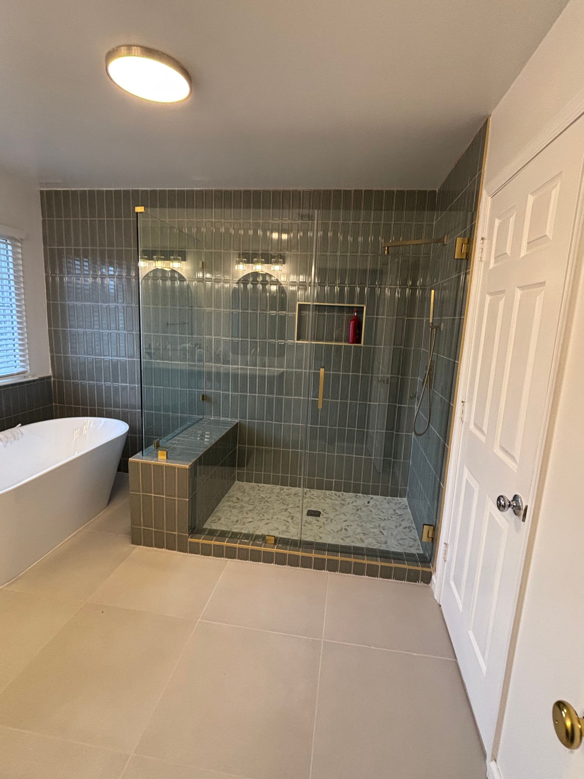 Modern bathroom with a tiled shower, freestanding tub, and a white door.
