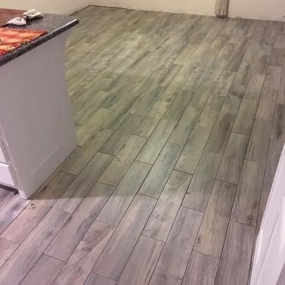 Light gray, wood-look plank flooring installed in a room next to a white kitchen counter.